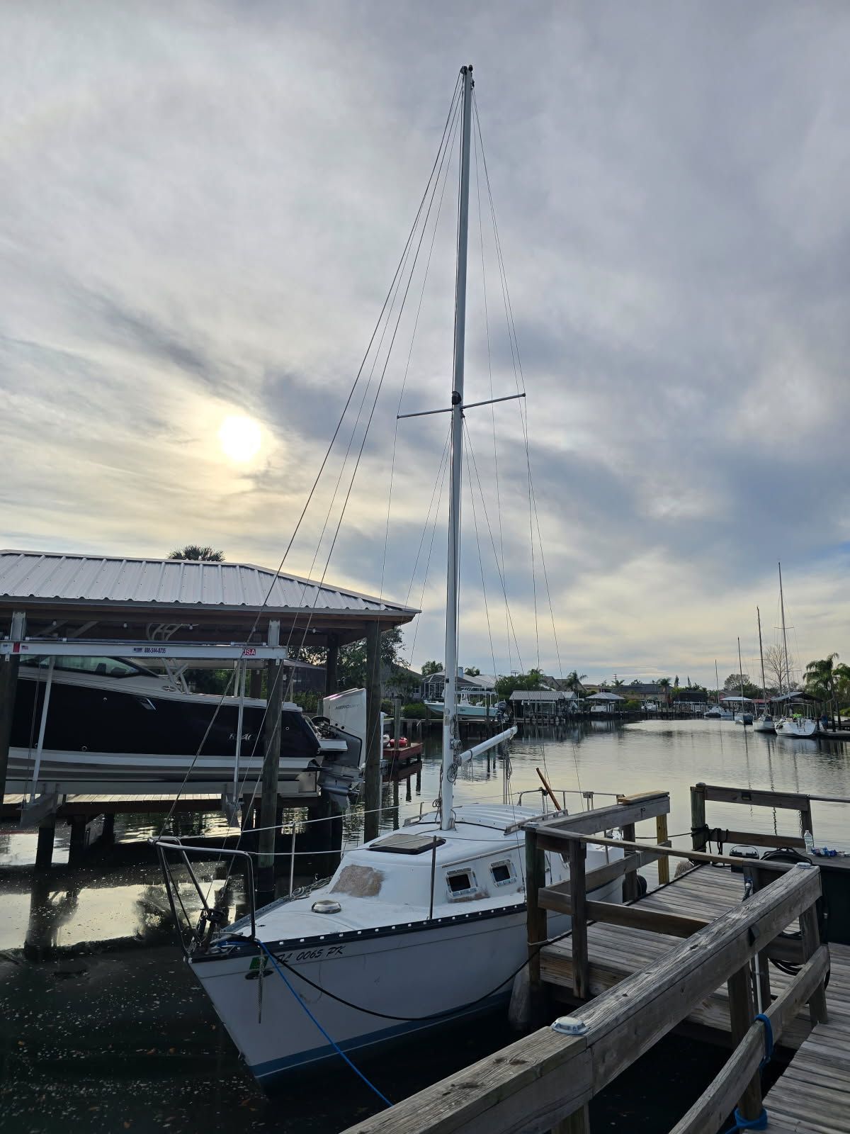A 1982 Hunter 25.5 sailboat docked at a wooden pier in a calm harbor.