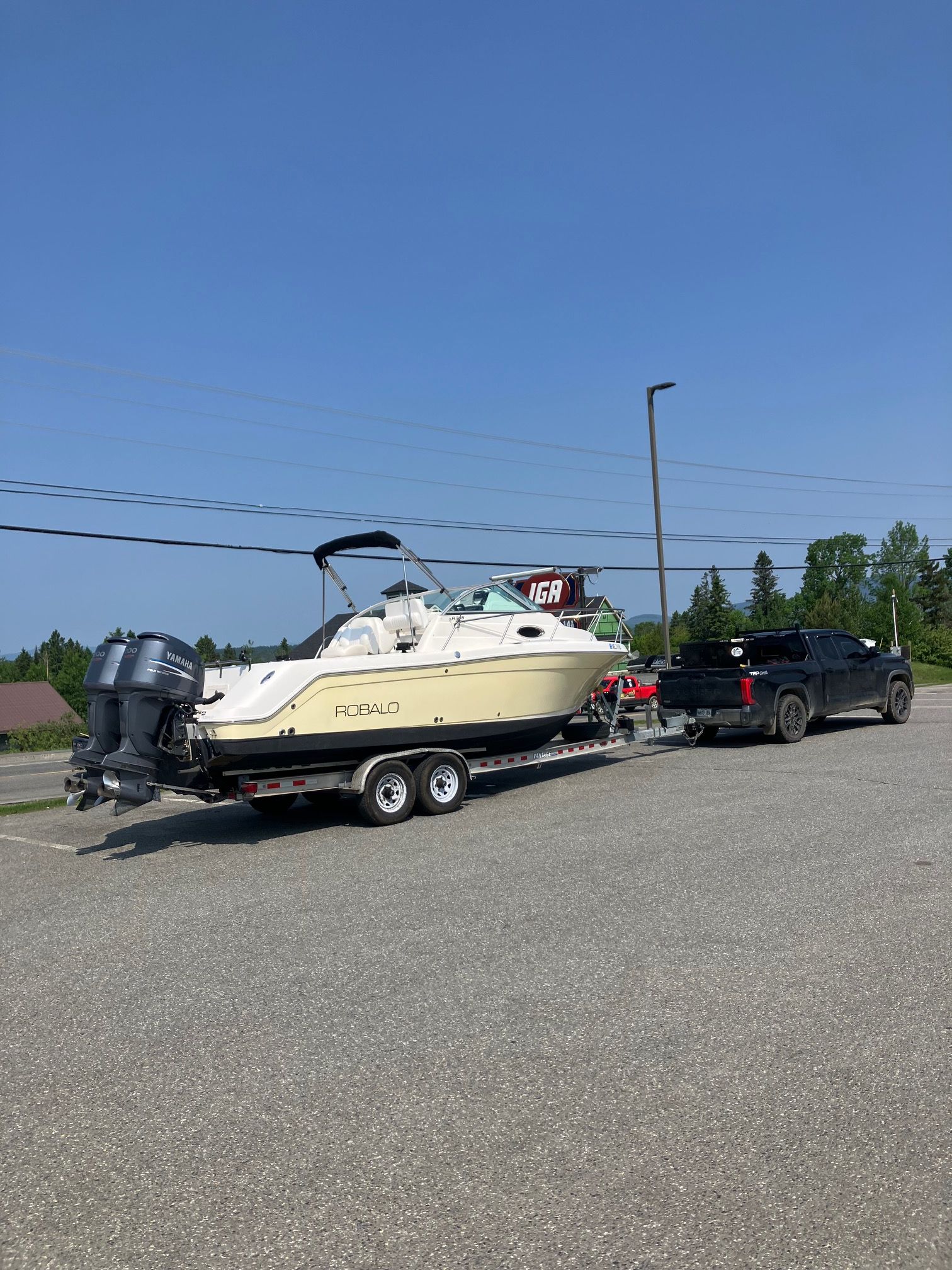 A 2006 Robalo R265 Walkaround boat on a trailer, towed by a black pickup truck.
