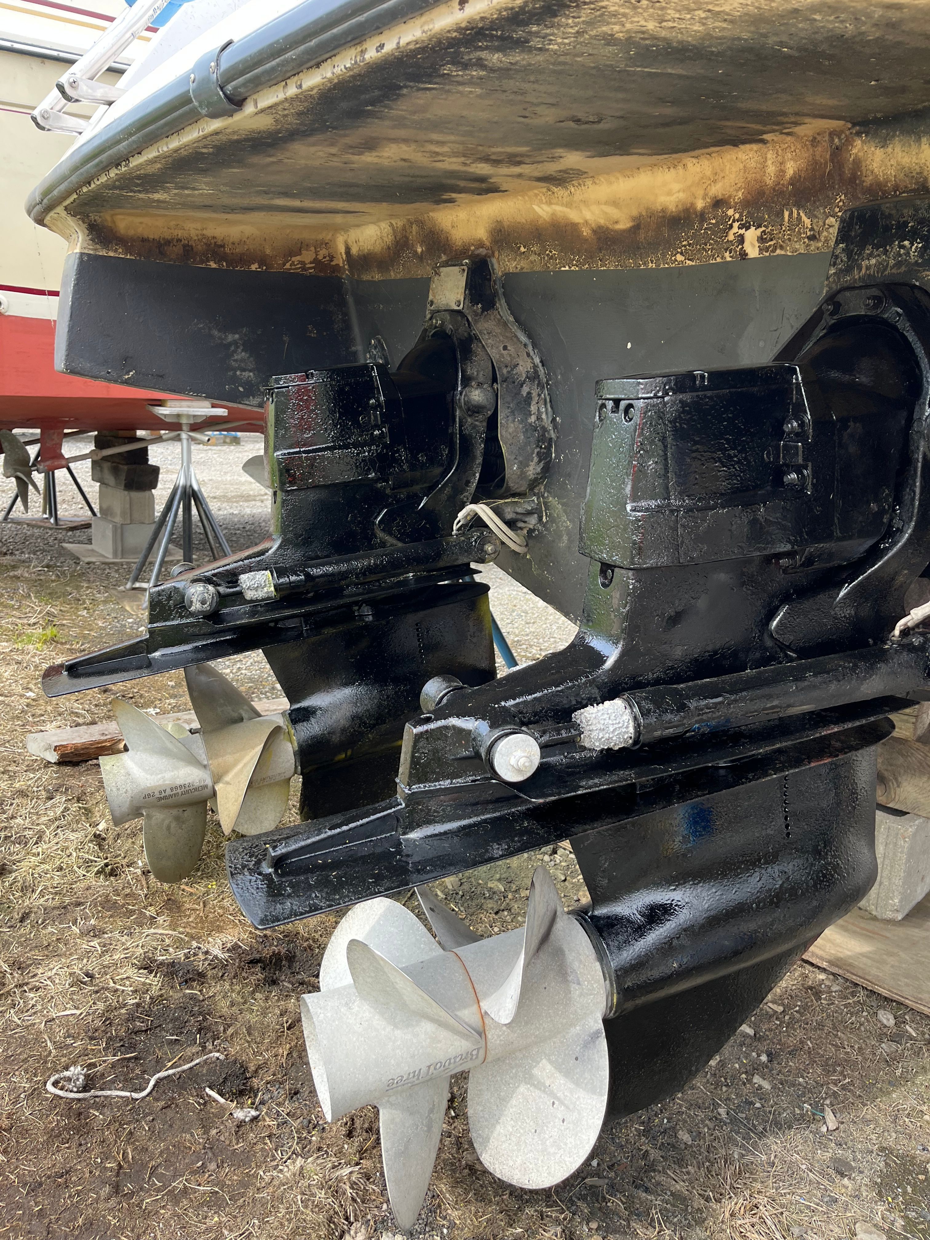 Two black boat engines with propellers on dry ground.