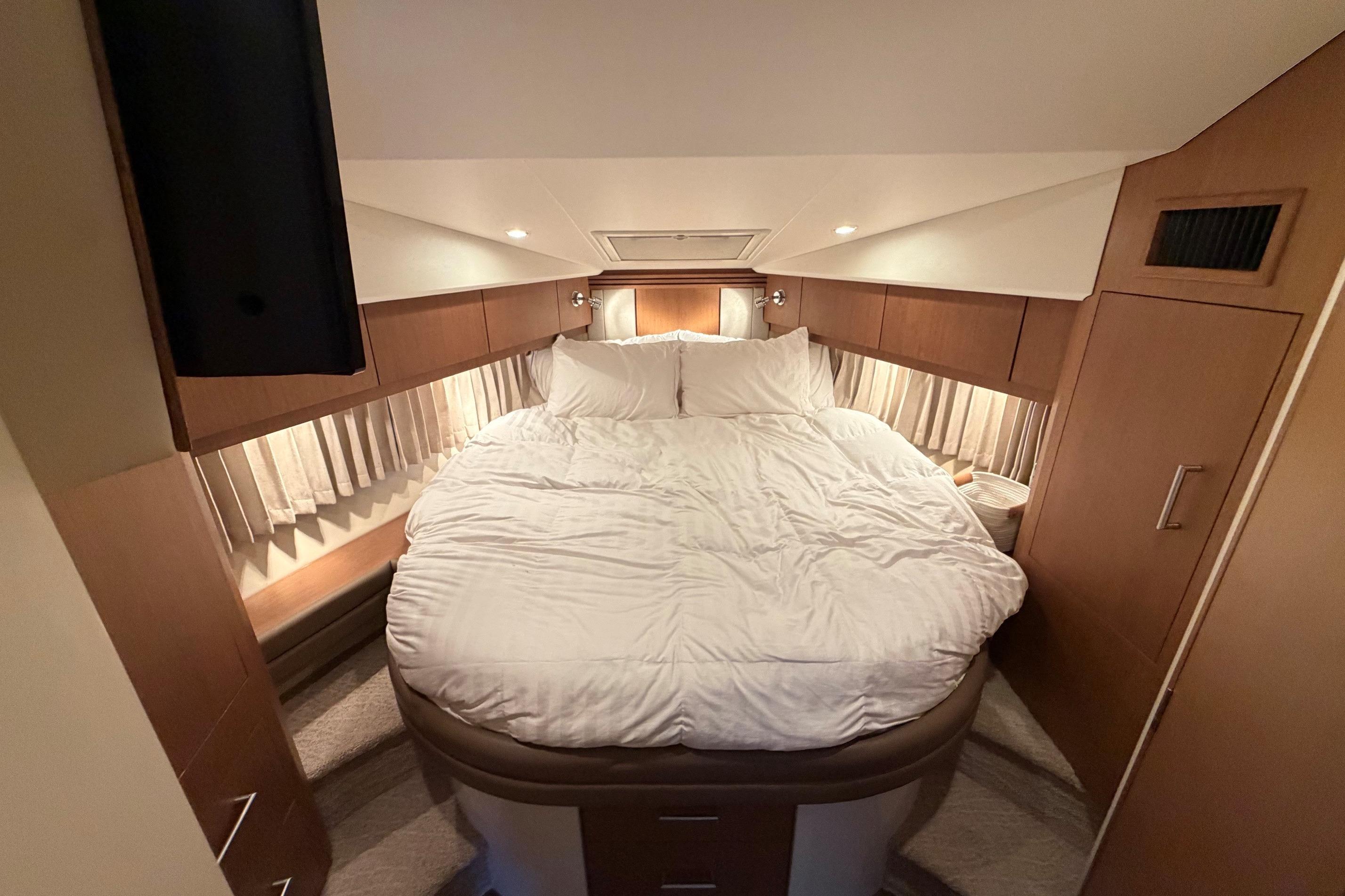 Luxurious bedroom interior of 2011 Carver 44 Sojourn yacht with cozy bedding.