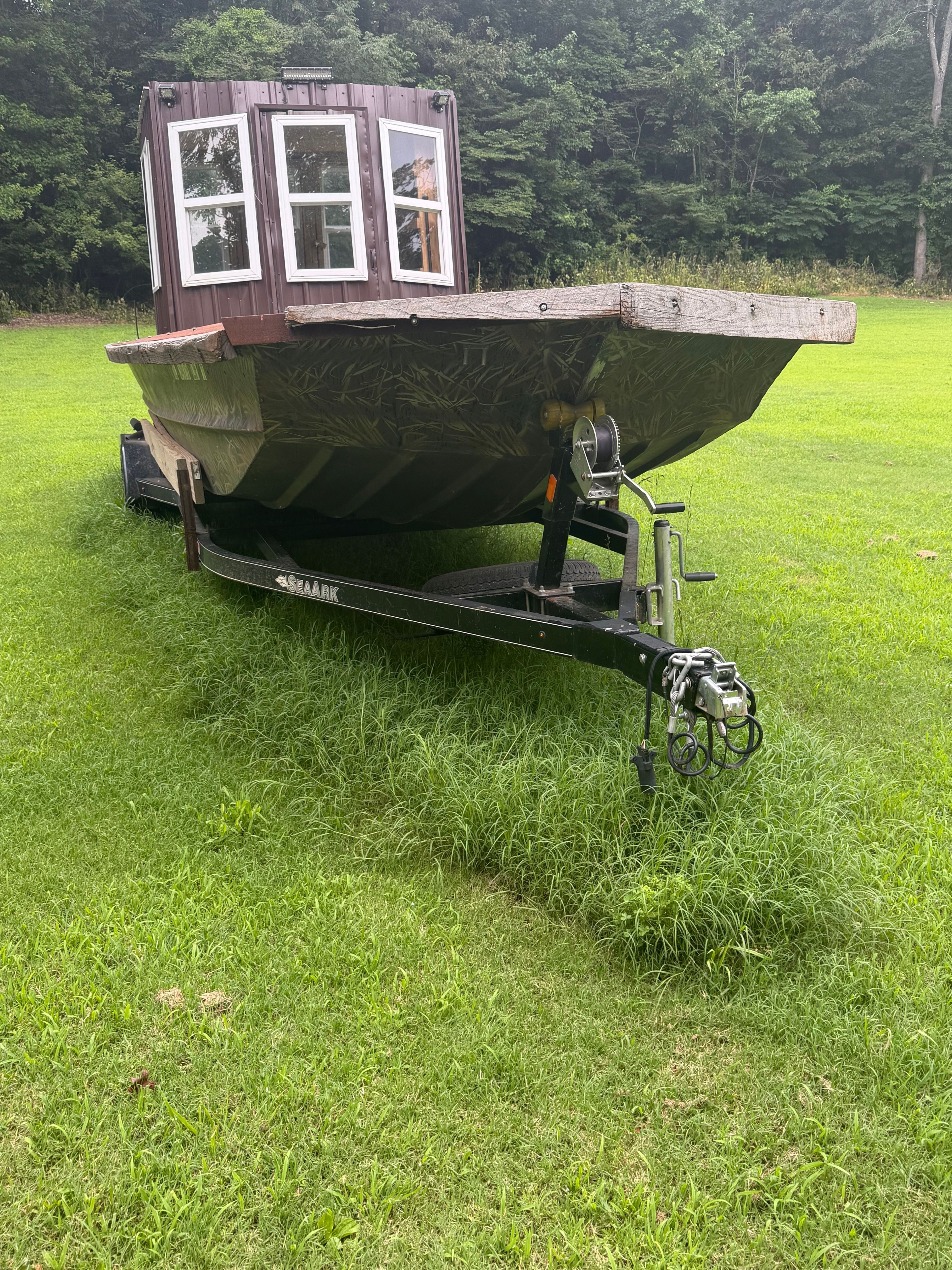 A 24-foot SeaArk boat on a trailer, parked on a green lawn.