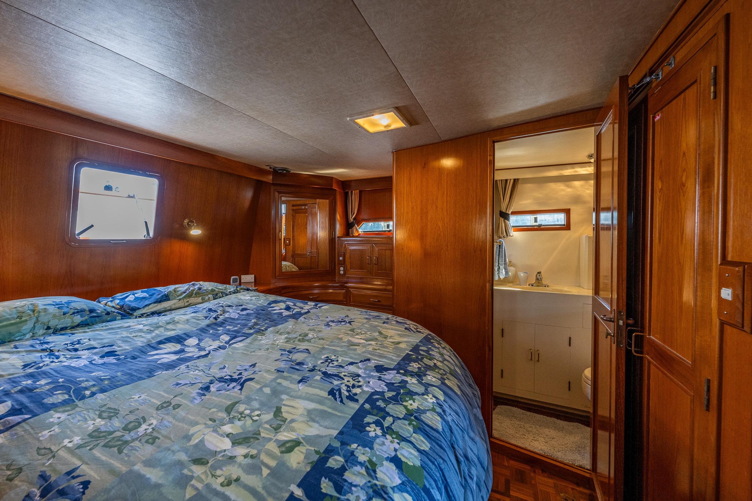 Luxurious 1989 Ocean Alexander 42 yacht bedroom with ensuite bathroom and elegant wood finishes.