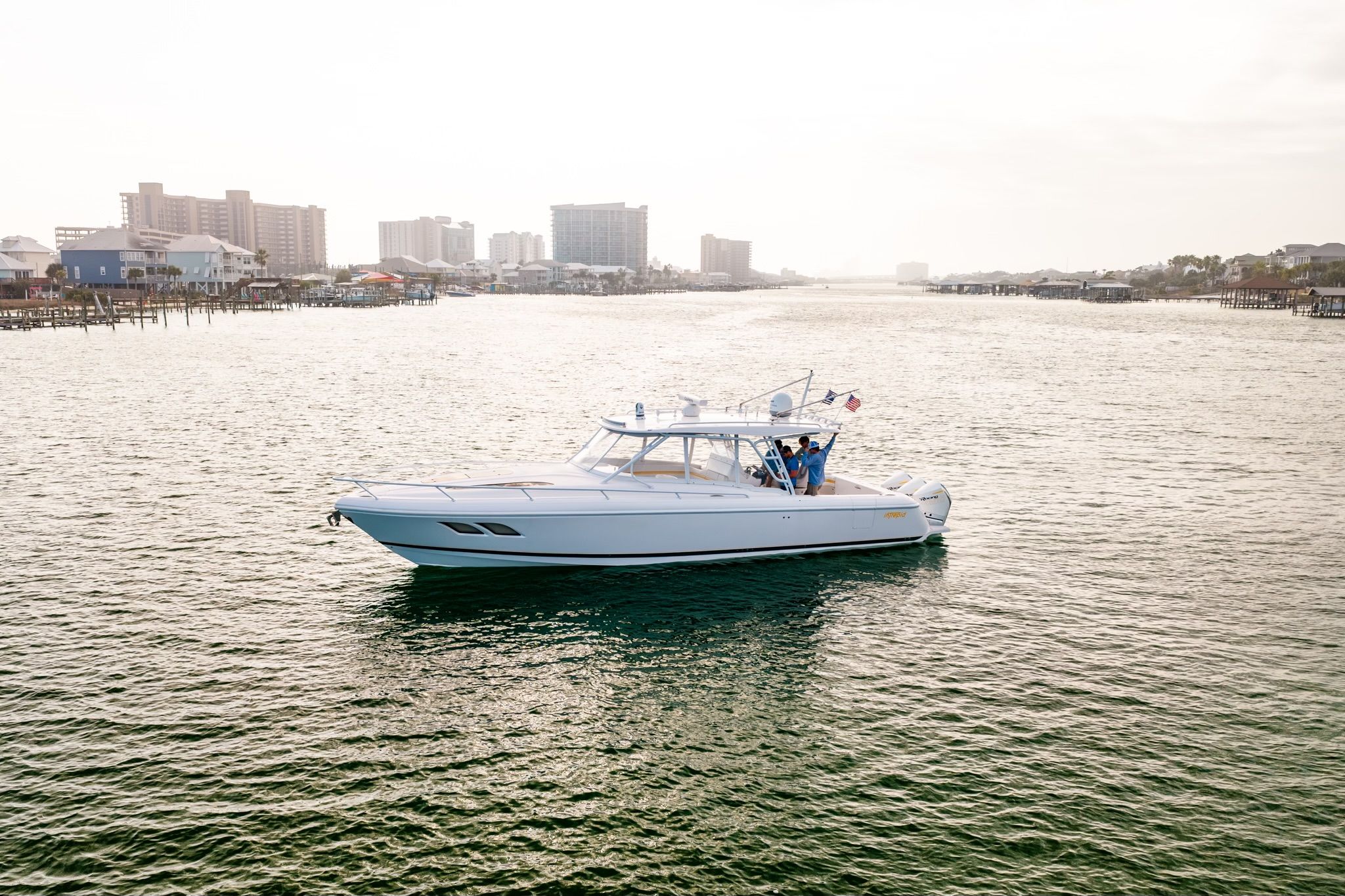 A 2020 Intrepid 409 Cuddy cruising on calm waters with a city skyline in the background.