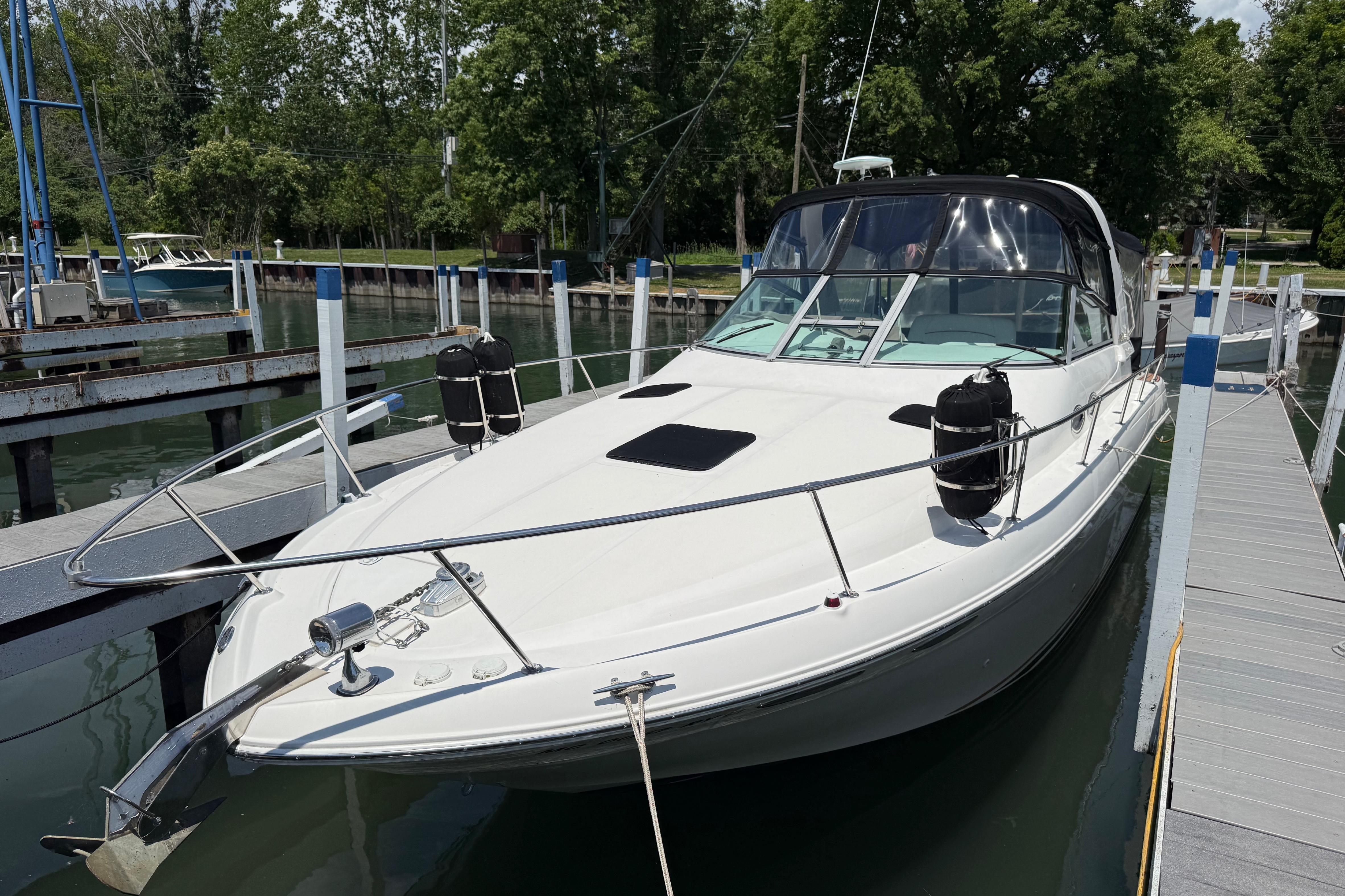 1999 Sea Ray Sundancer 310 docked at marina, surrounded by lush greenery.