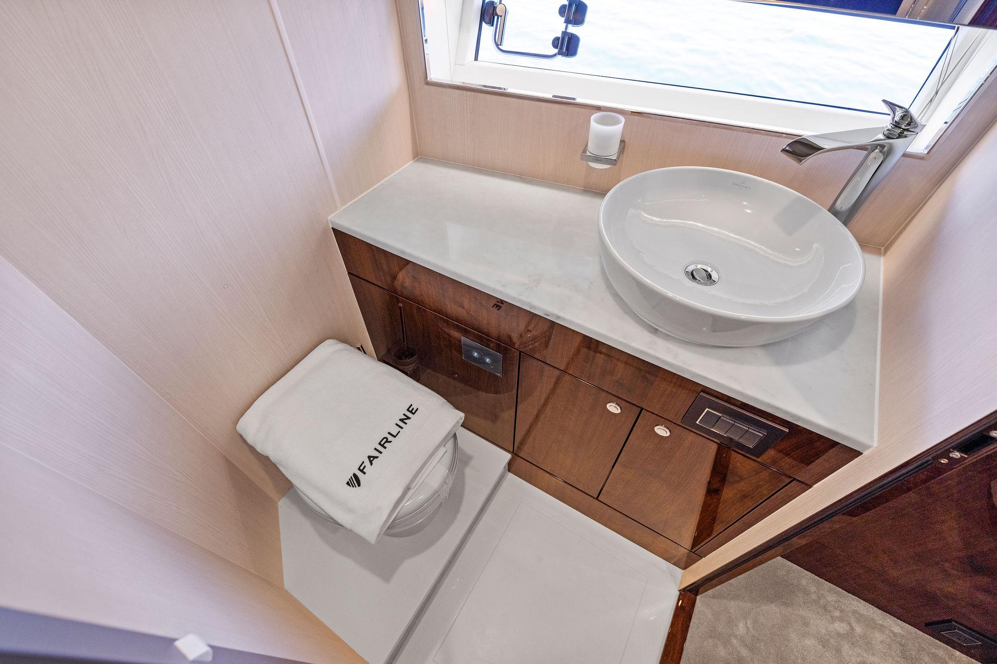 Luxurious bathroom in 2024 Fairline Phantom 65 yacht with modern sink and elegant wood cabinetry.