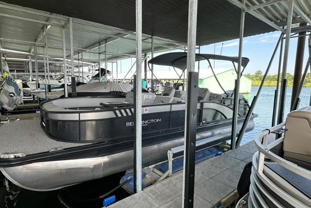 2021 Bennington L Bowrider 25 Quad Bench pontoon boat docked under a covered marina.