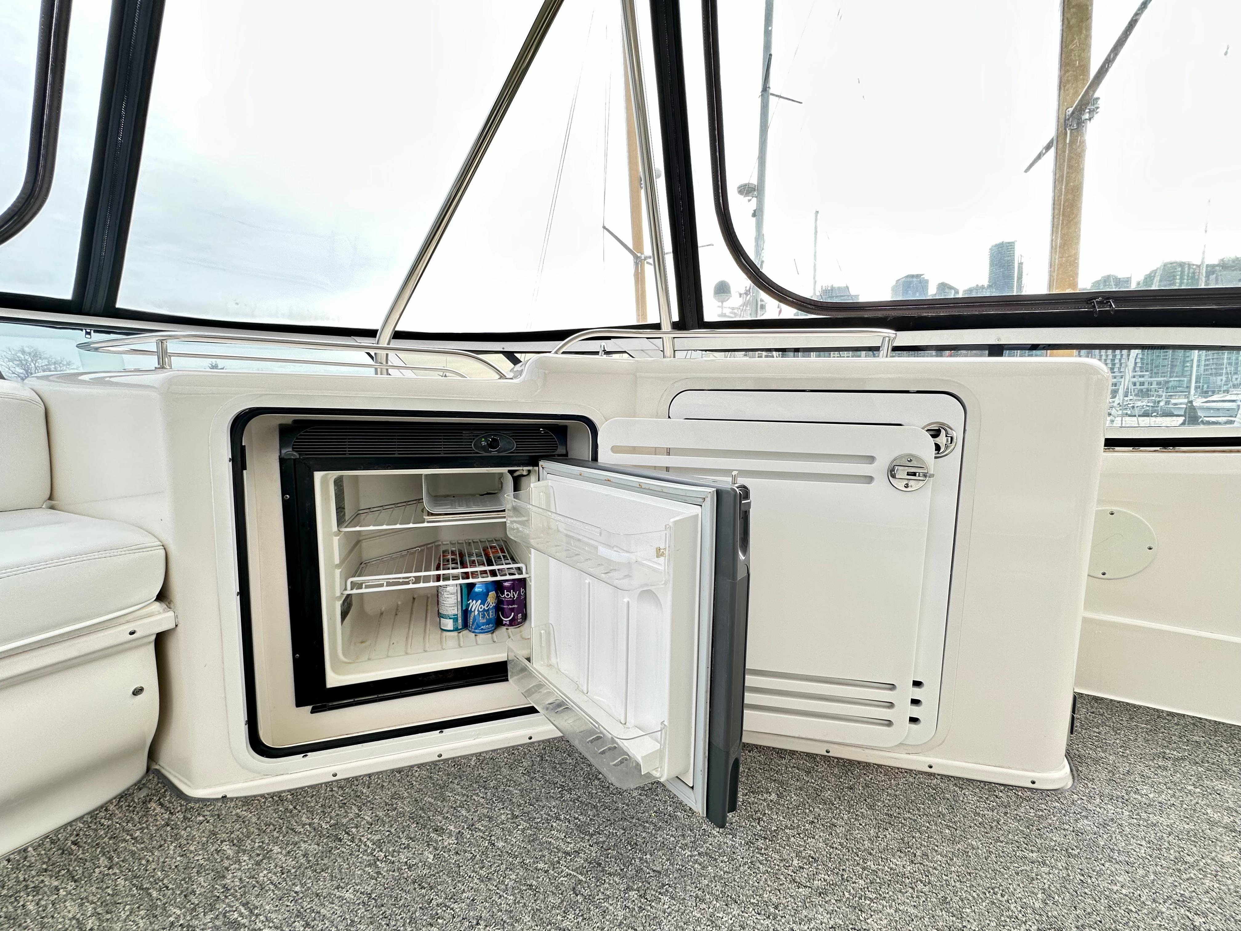 Mini fridge on 2002 Sea Ray 560 Sedan Bridge yacht, open with drinks inside.