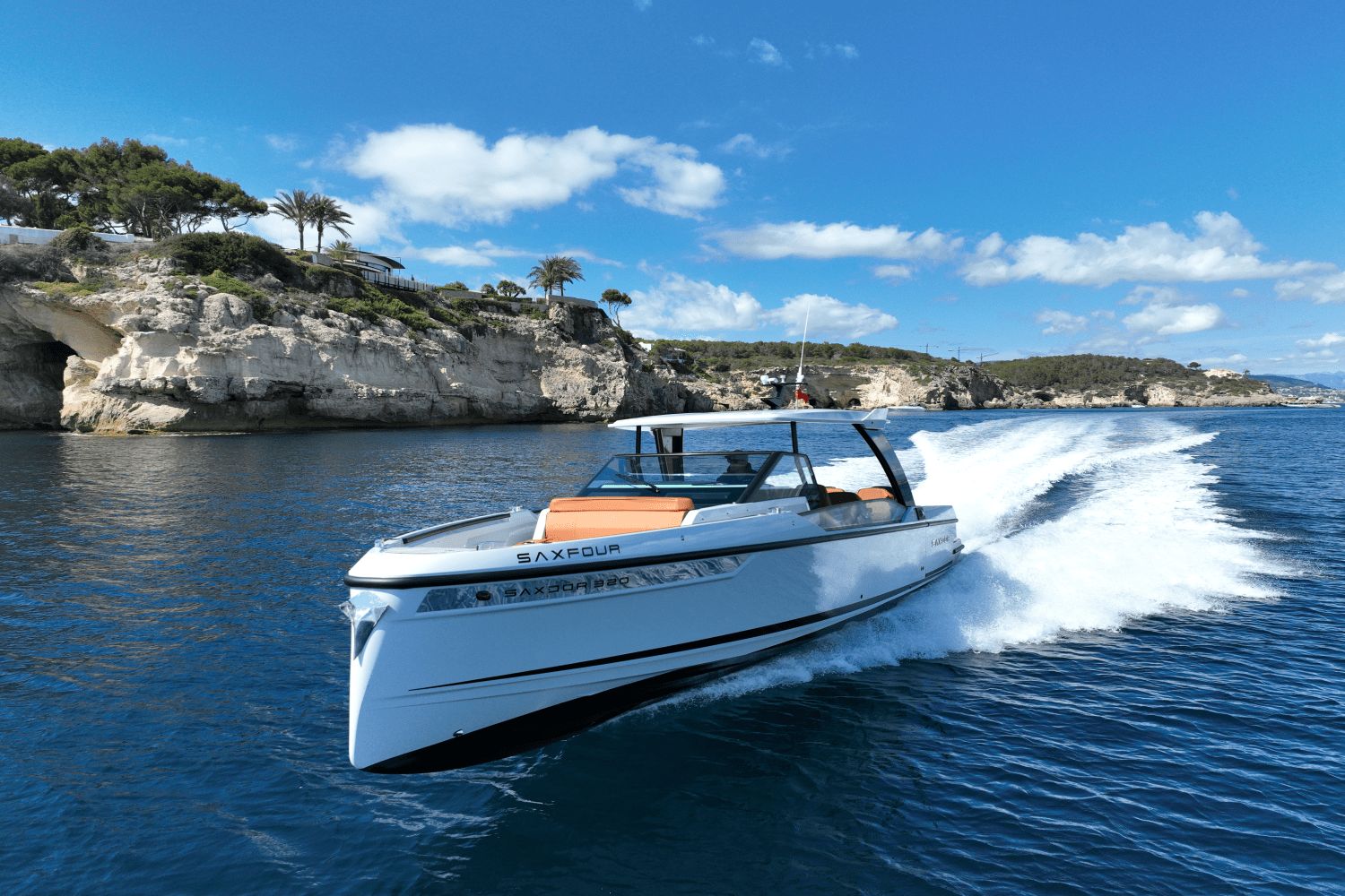 Saxdor SX320 GTO from 2027 speeding on blue water near rocky coastline.