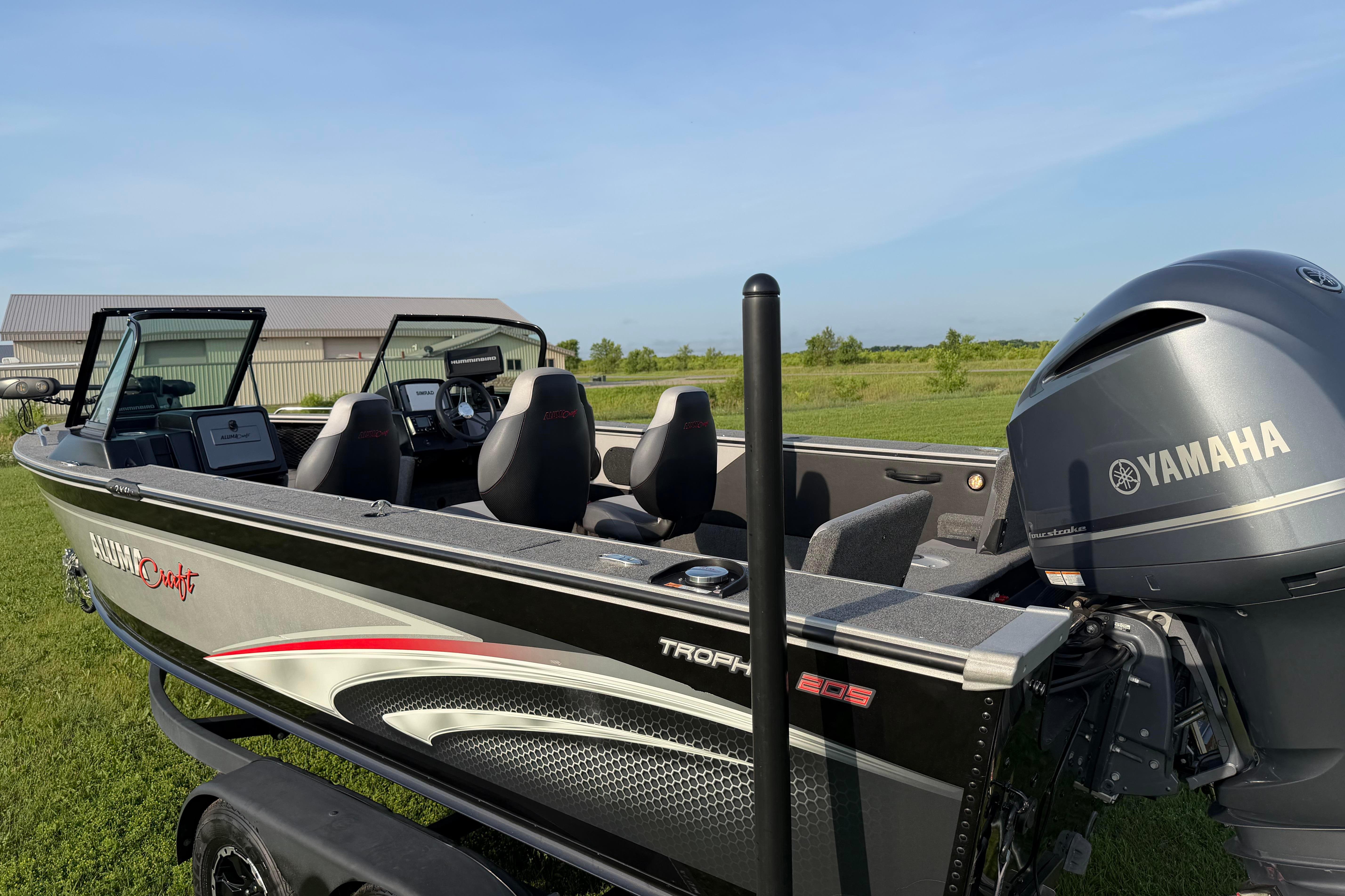 2019 Alumacraft Trophy 205 boat with Yamaha engine, parked on grass under clear sky.