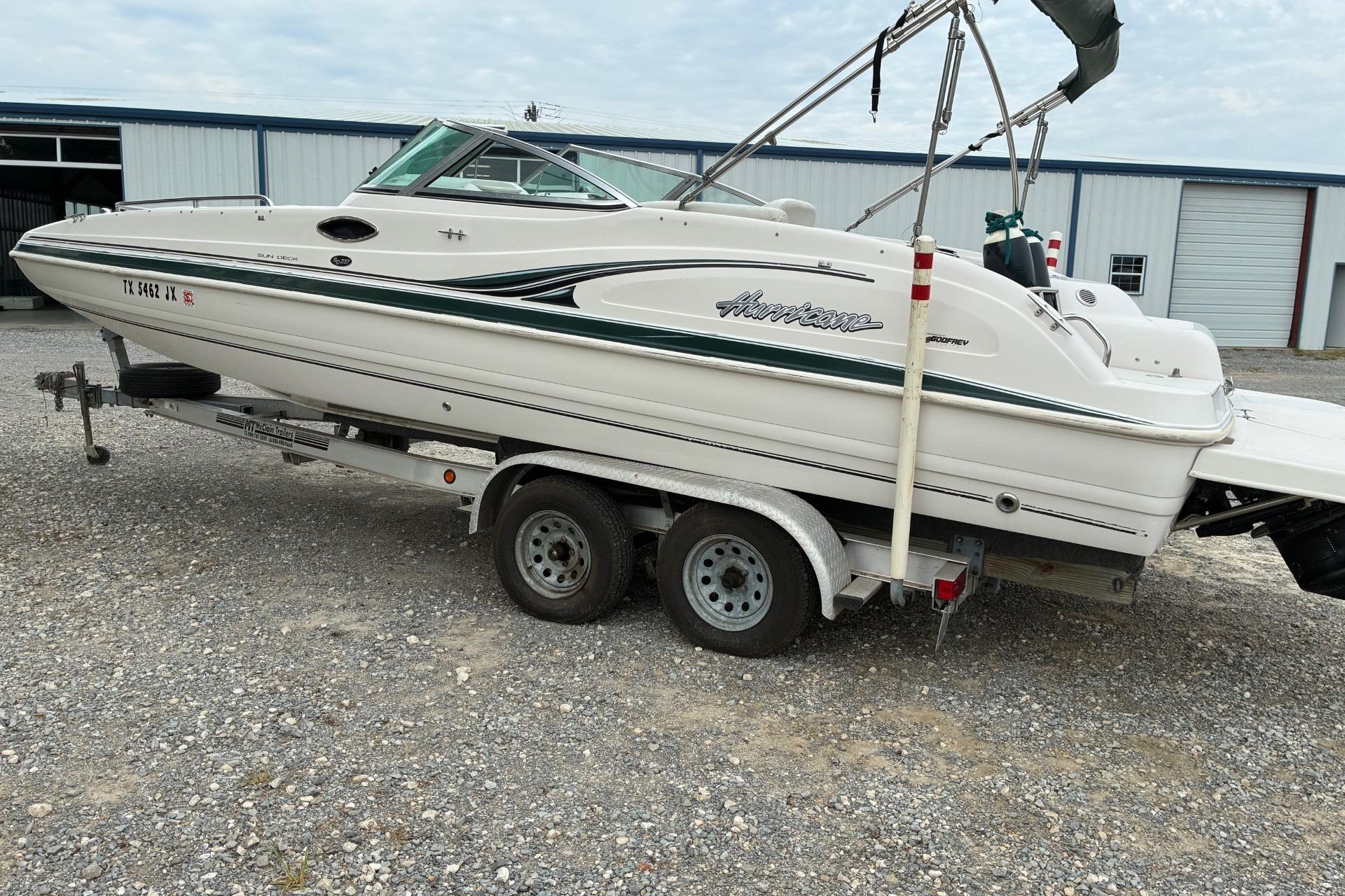 2003 Hurricane 234 SD boat on trailer, parked outdoors near a warehouse.