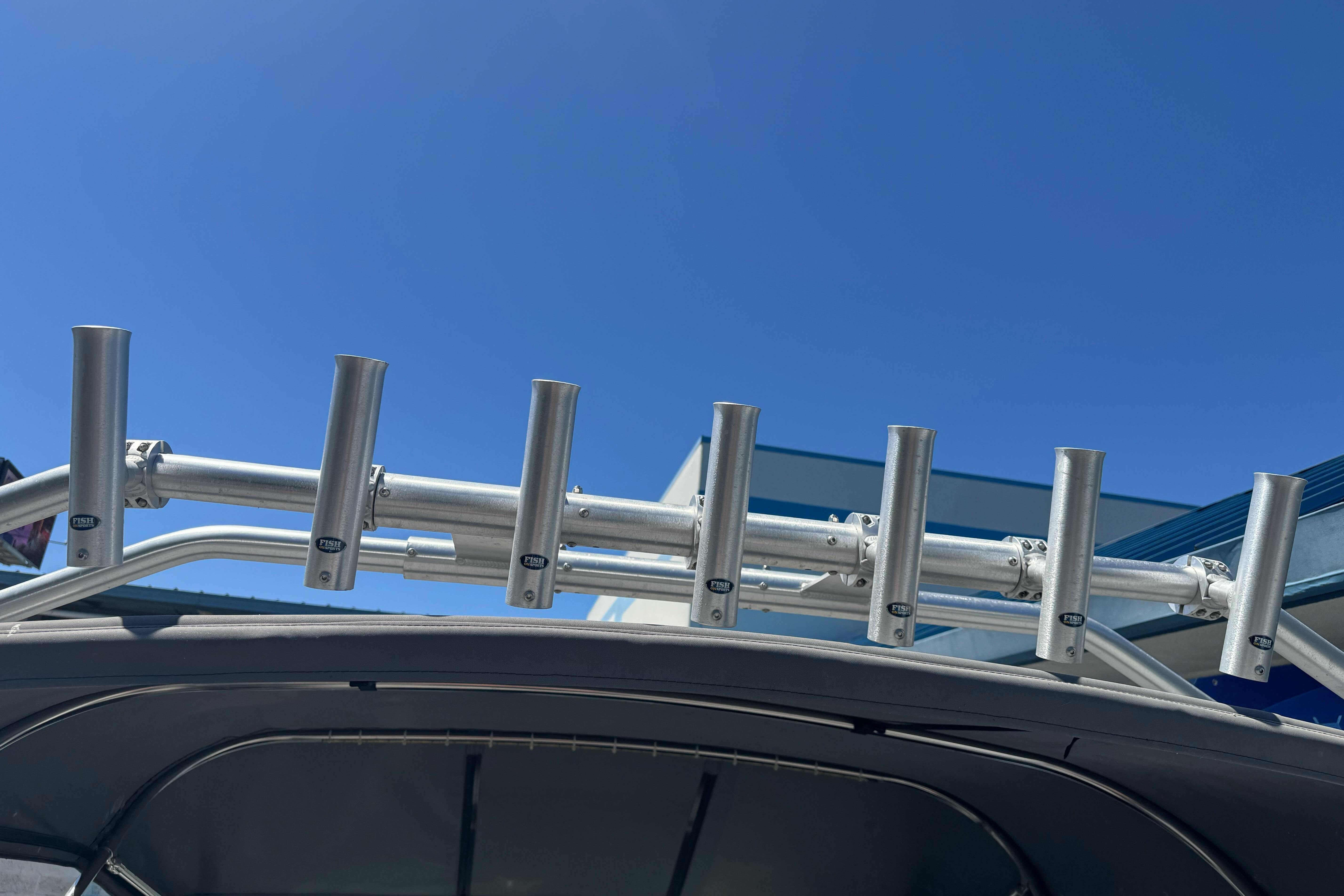 Aluminum rod holders on a 2014 River Hawk 19 GB boat under clear blue sky.