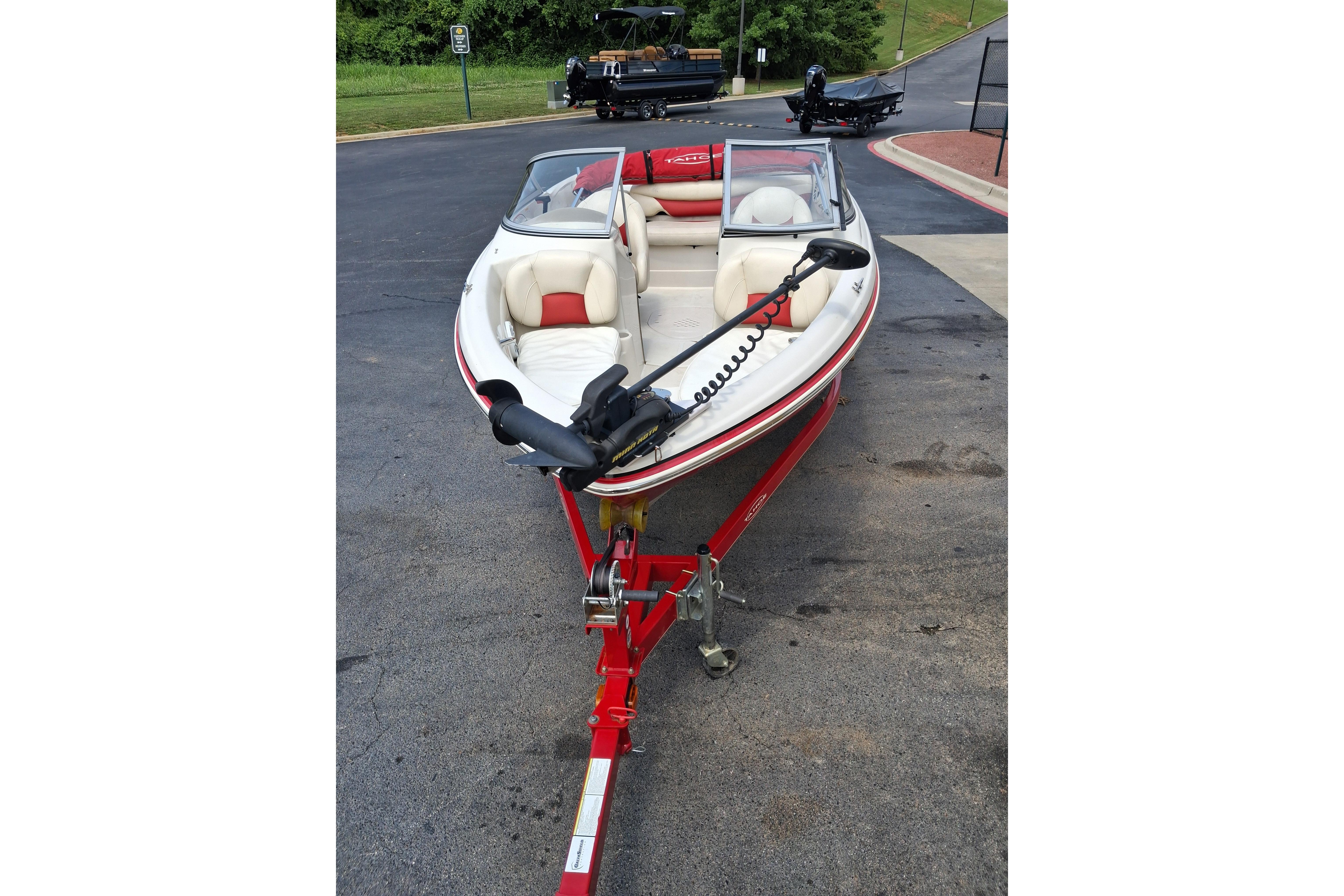 2014 Tahoe Q5i boat on trailer, featuring red and white design, parked outdoors.