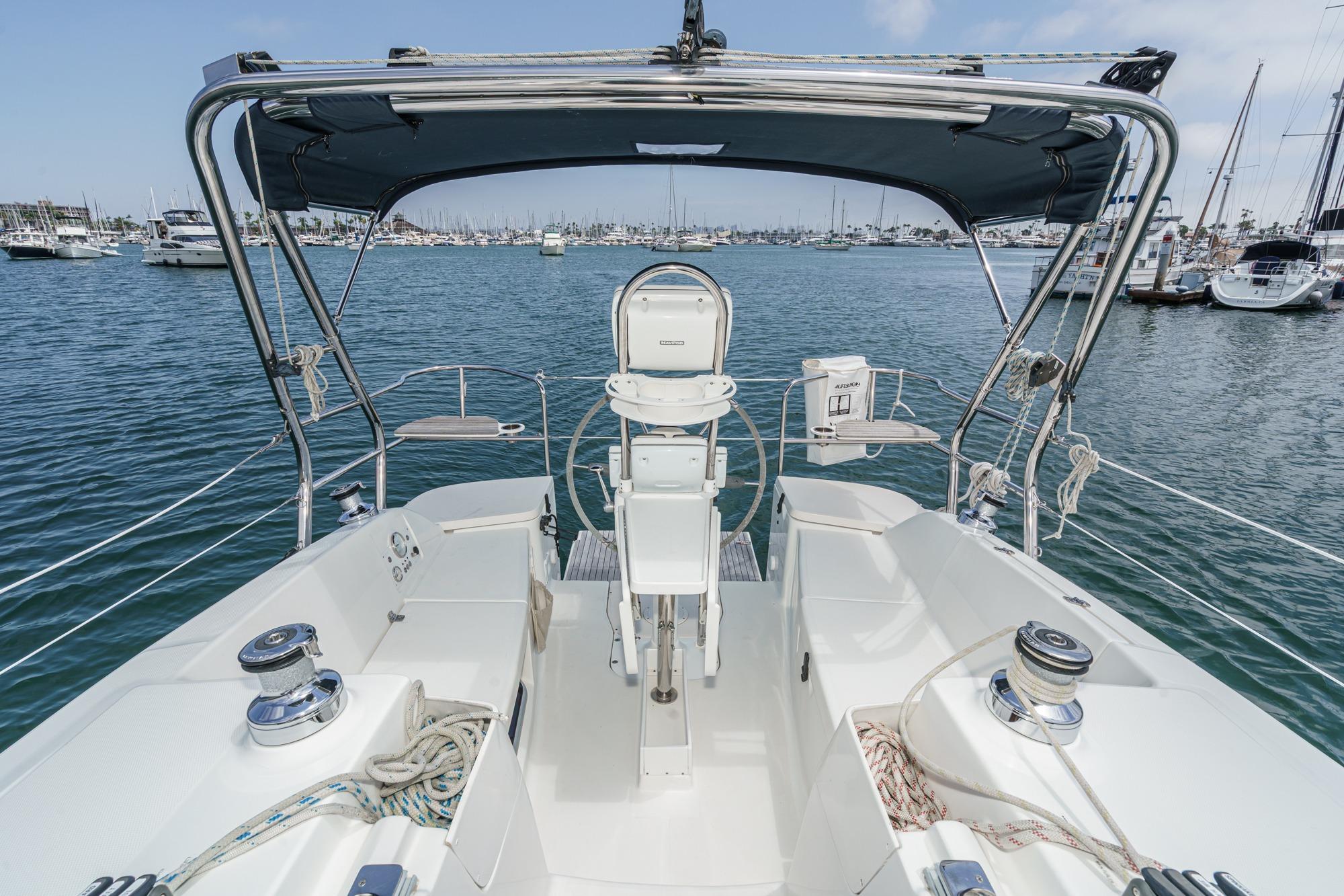 Cockpit view of 2015 Hunter 33 sailboat in marina, featuring steering and winches.