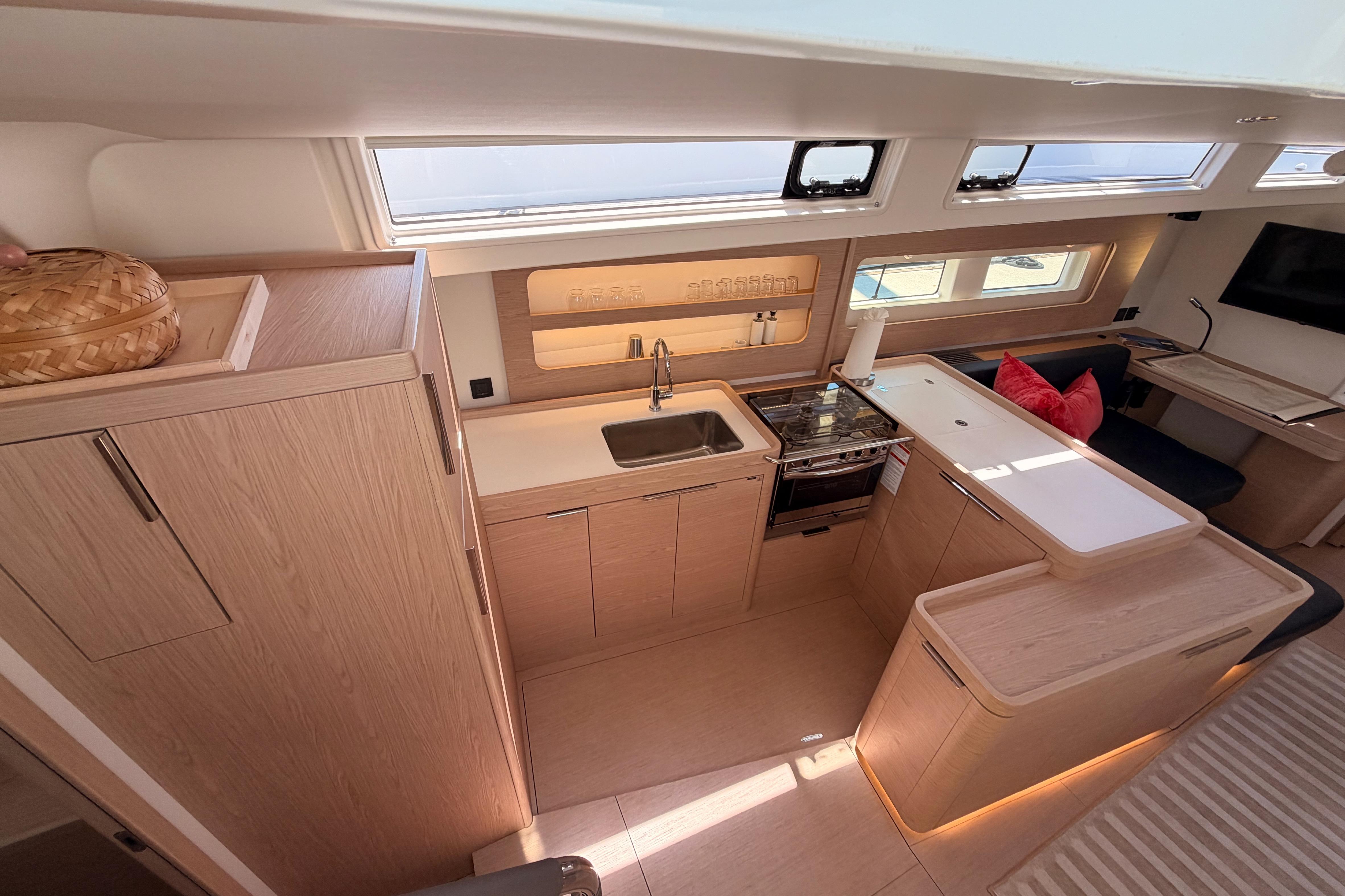 Modern kitchen interior of 2022 Beneteau Oceanis Yacht 54 with sleek wood finishes.