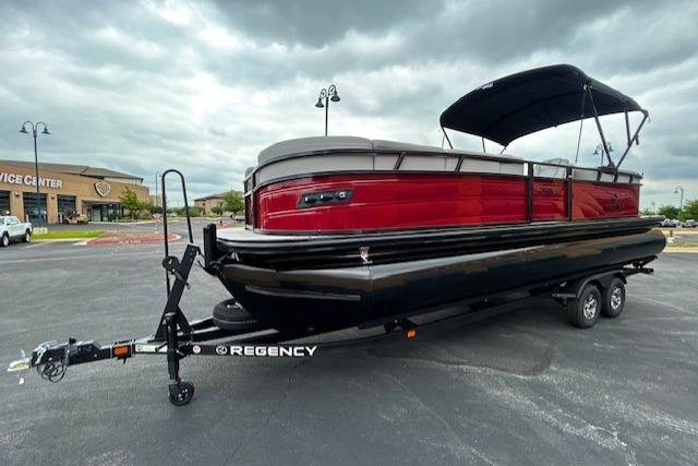 Regency 250 DL 2026 pontoon boat on trailer, red and black design.