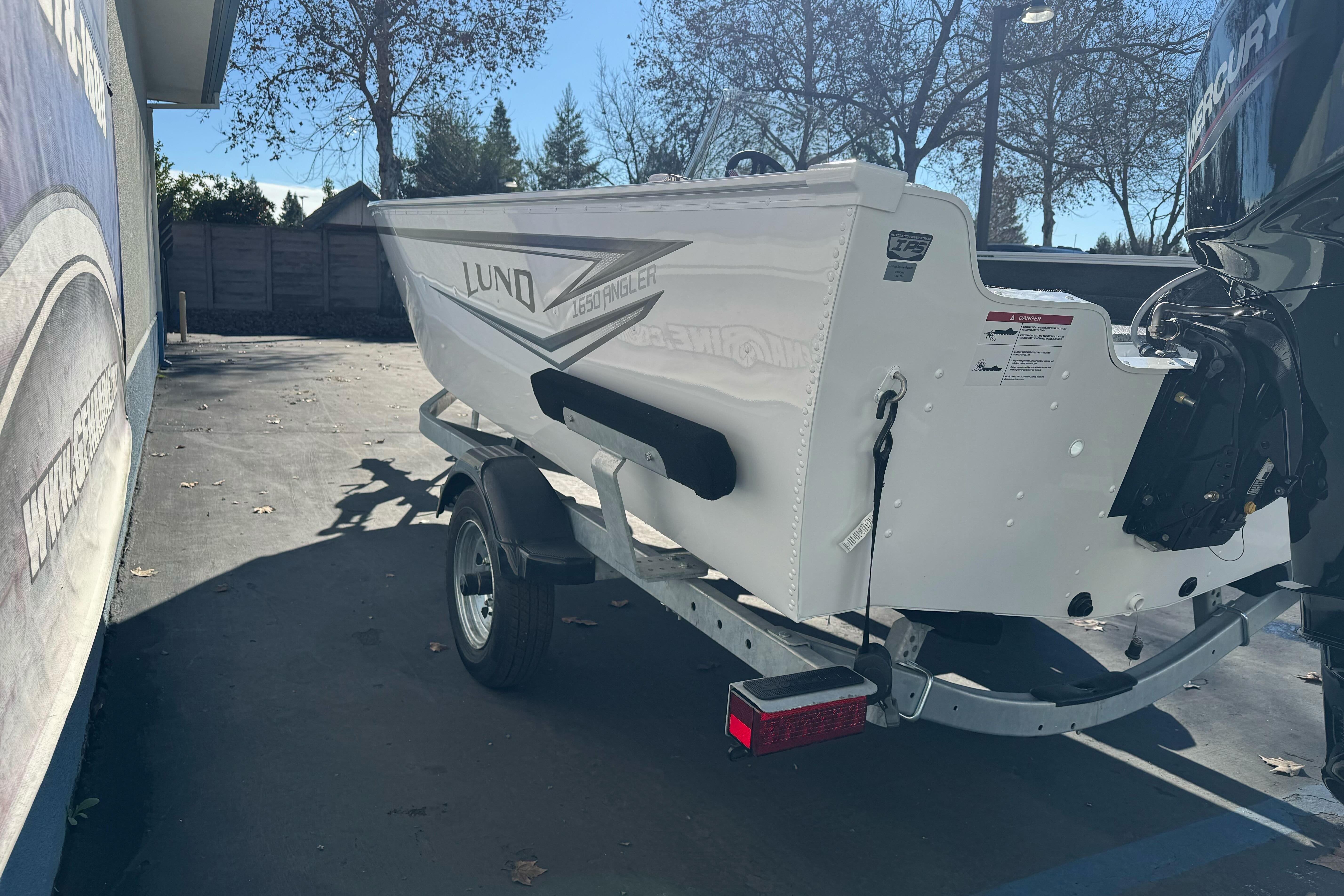 2026 Lund 1650 Angler SS boat on trailer, parked outdoors in sunny setting.