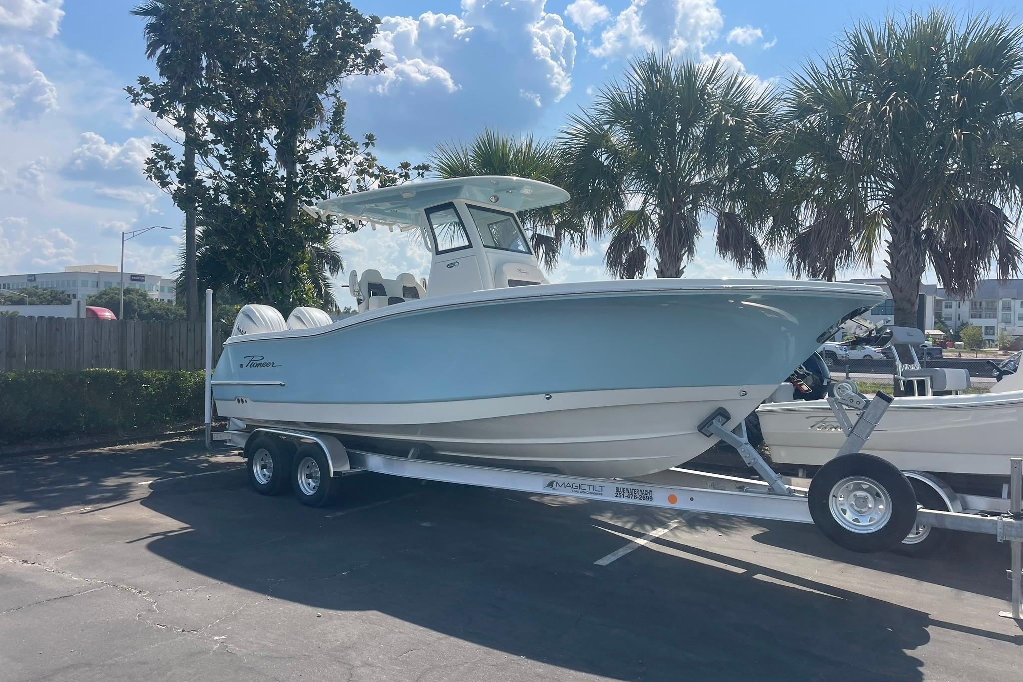 2026 Pioneer 250 Pelagic boat on trailer, parked under palm trees in sunny weather.