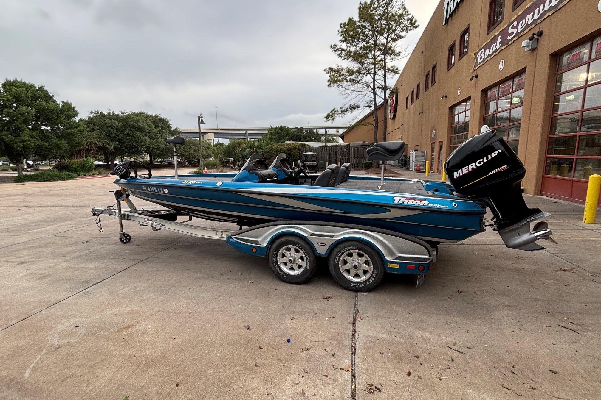 2009 Triton 22 TrX boat with Mercury engine on trailer, parked outside service center.