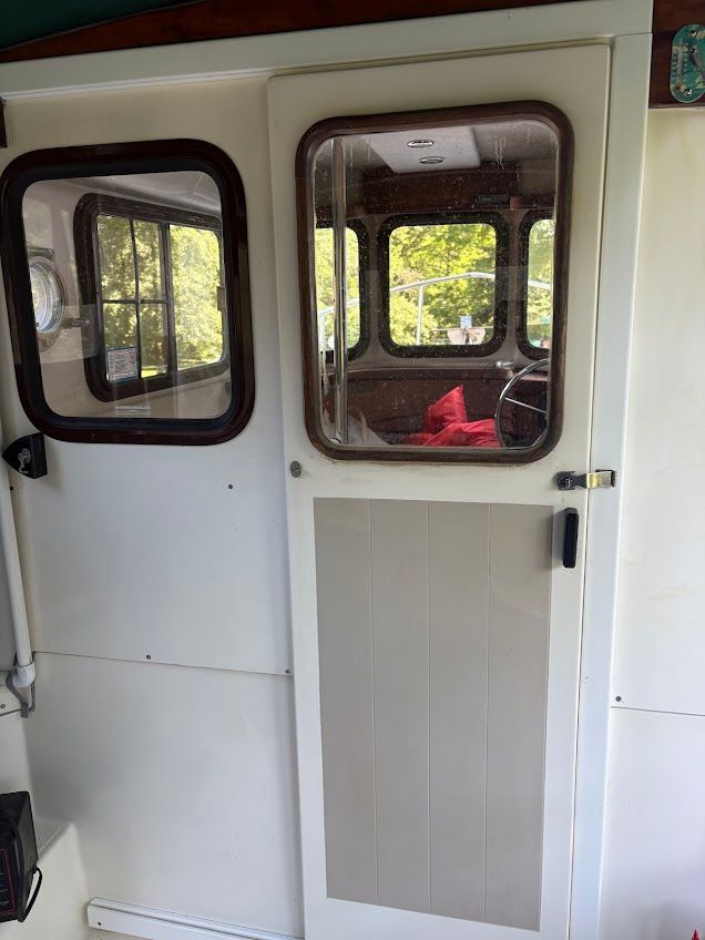 The cabin door of a 2007 Ranger Tugs R-21 EC with windows and a handle.