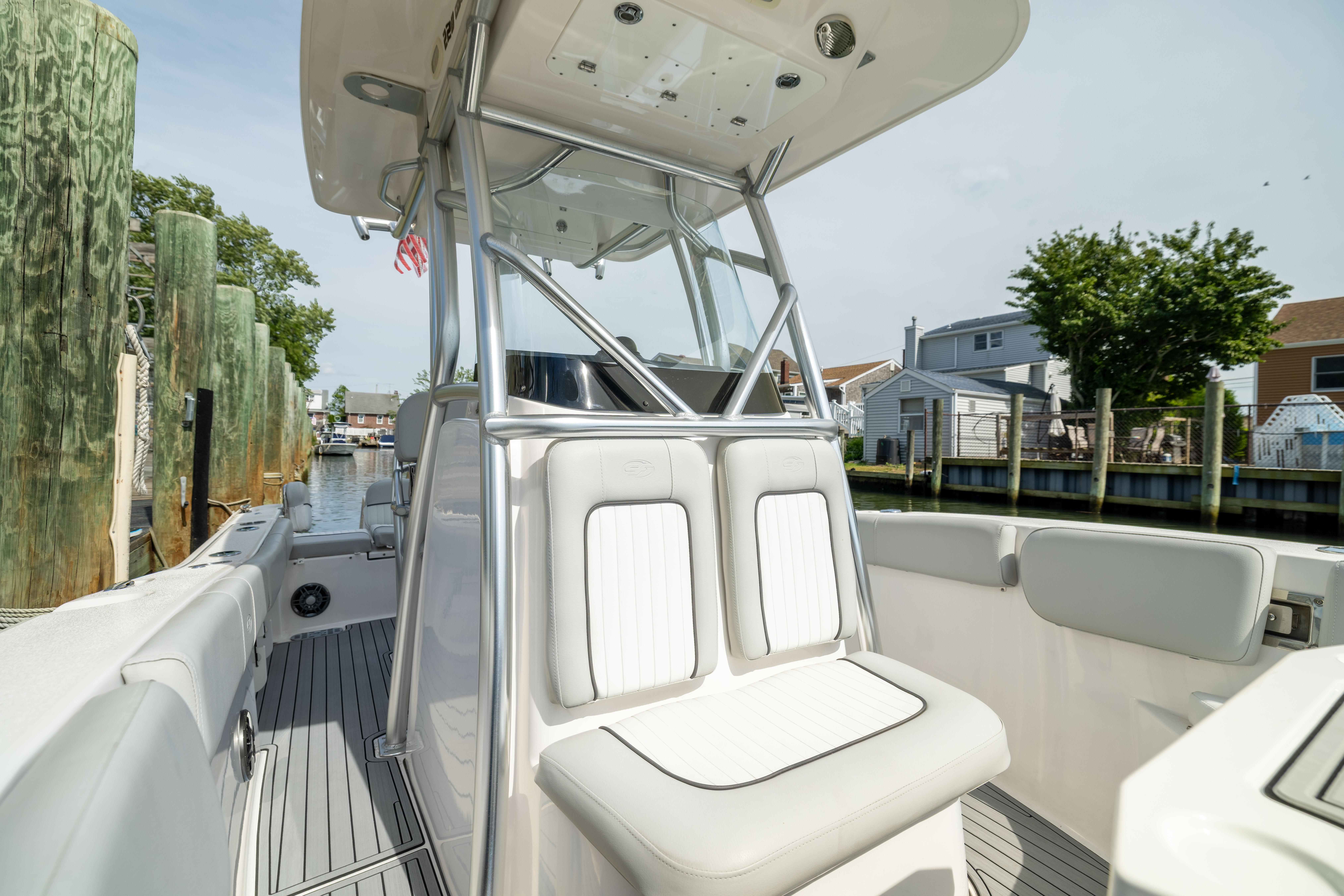 2023 Sea Fox 228 Commander boat interior with seating and console, docked near waterfront homes.