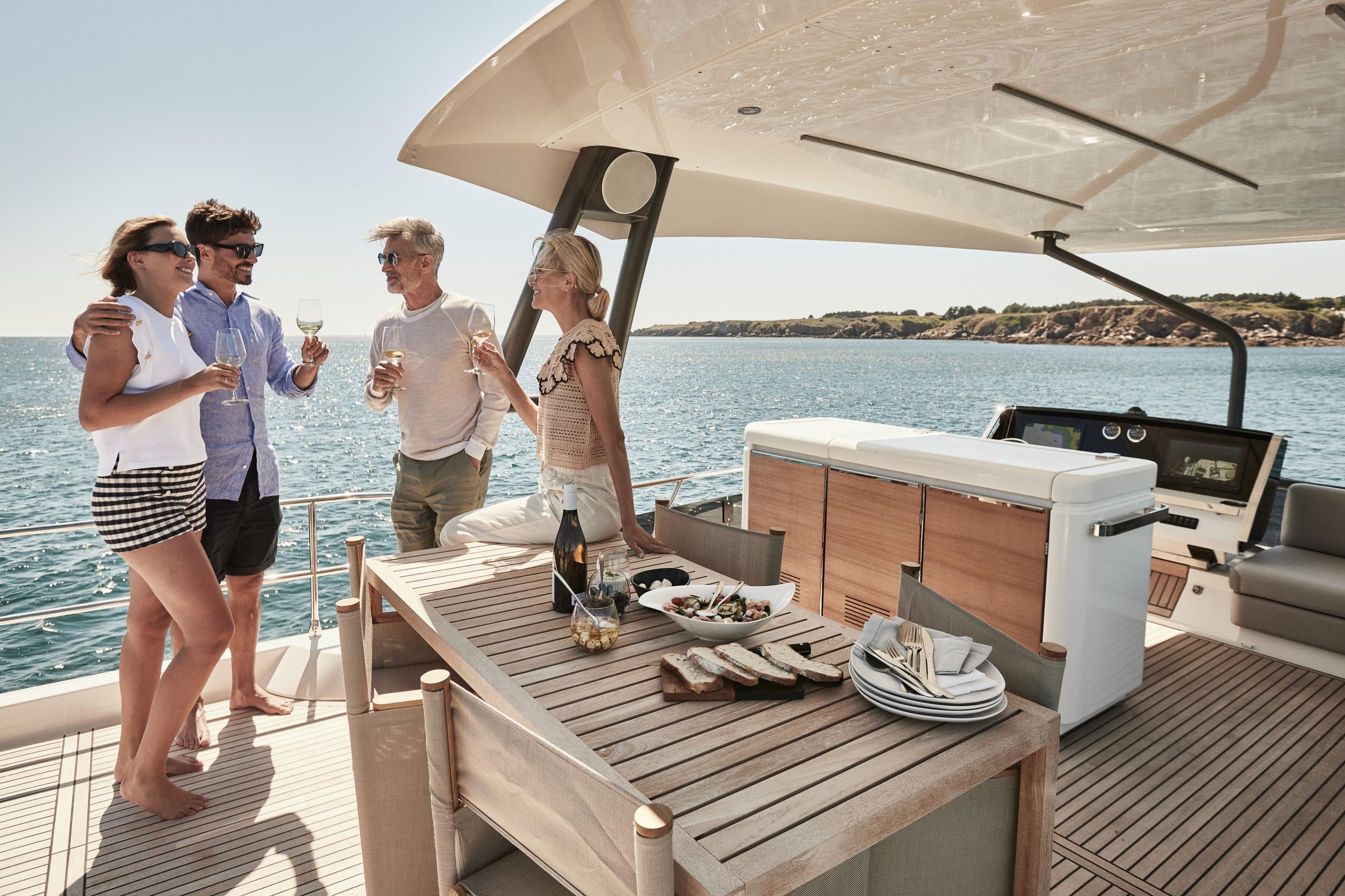 People enjoying drinks on a 2026 Prestige X60 yacht, with ocean views.
