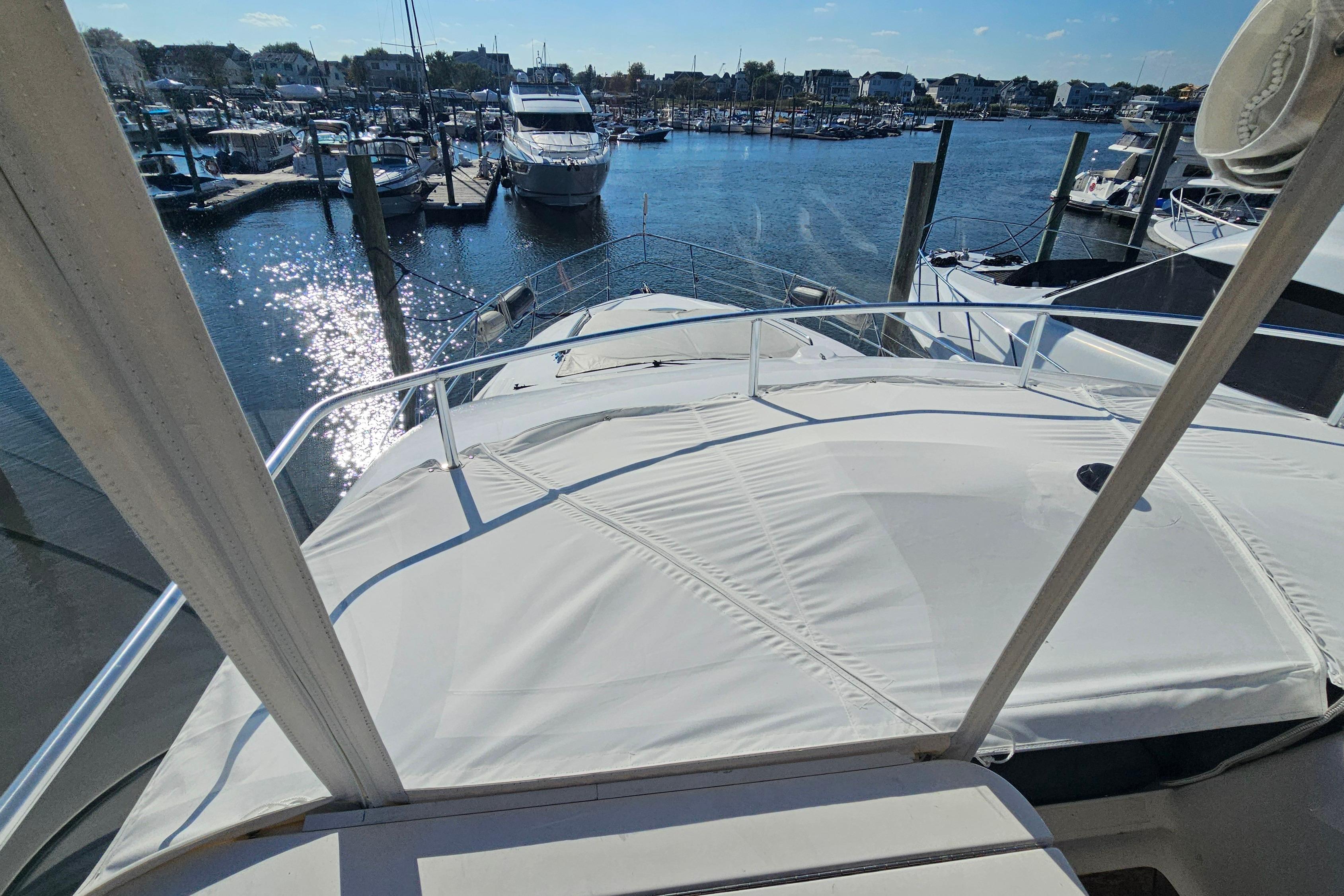 2005 Neptunus 56 Flybridge yacht docked at a marina under sunny skies.
