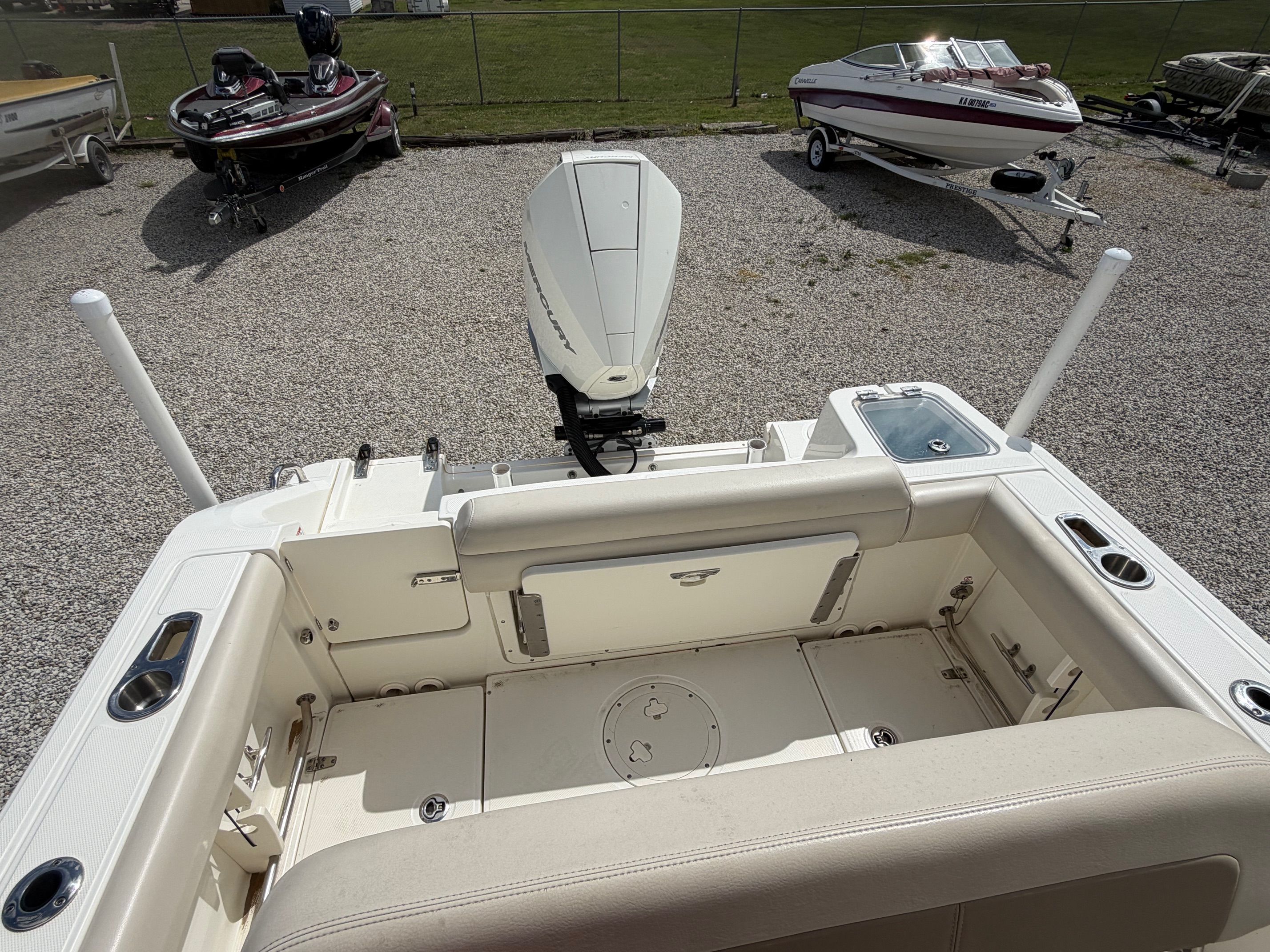 Boston Whaler 230 Outrage 2020 on gravel lot with other boats.