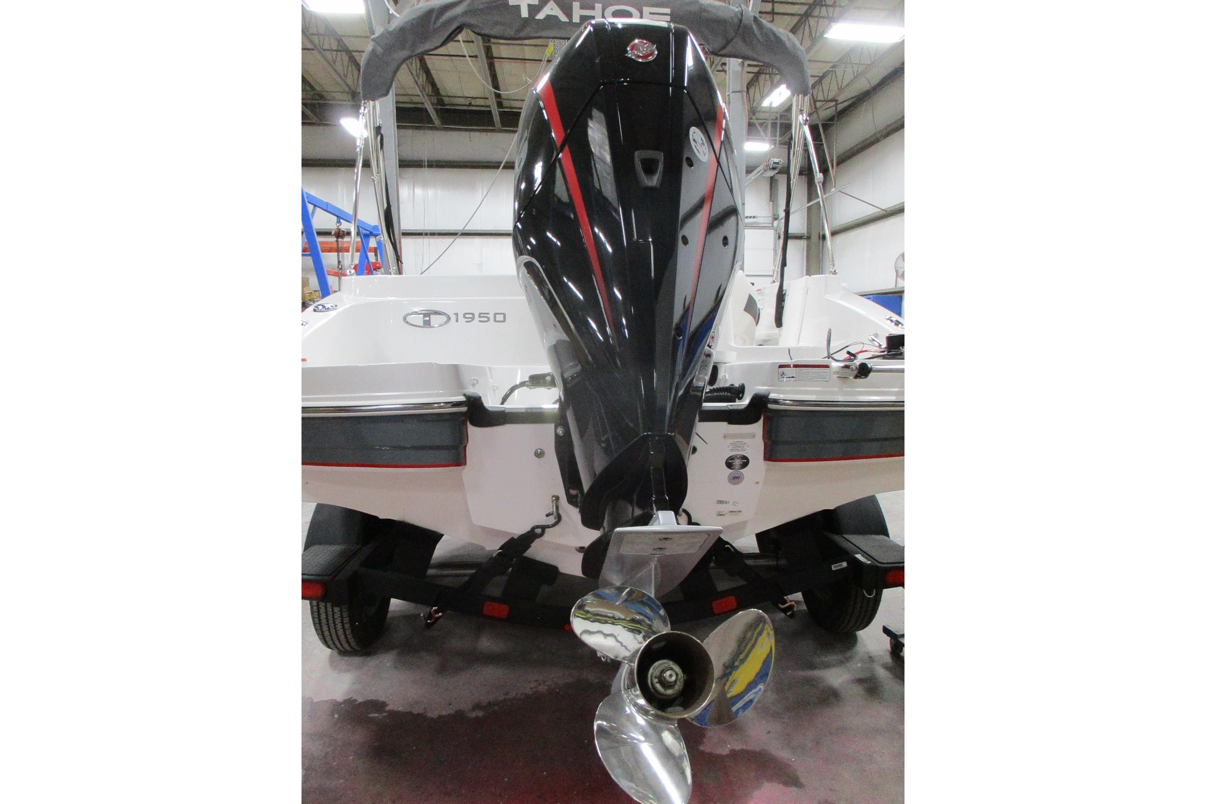 2024 Tahoe 1950 boat with powerful outboard motor in a showroom.