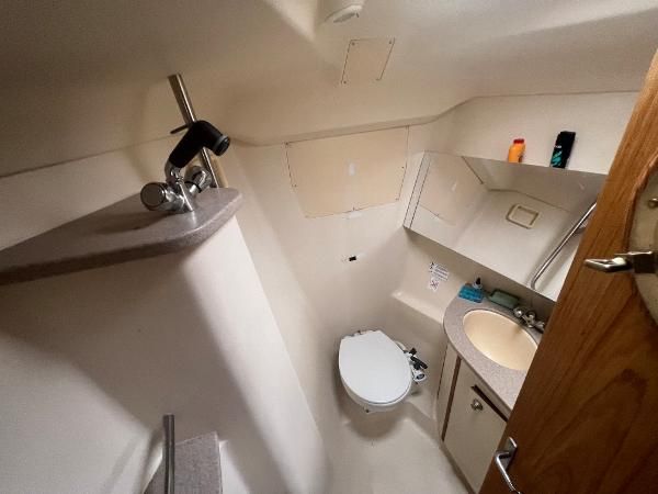 The image shows a boat bathroom with a toilet, sink, and mirror.
