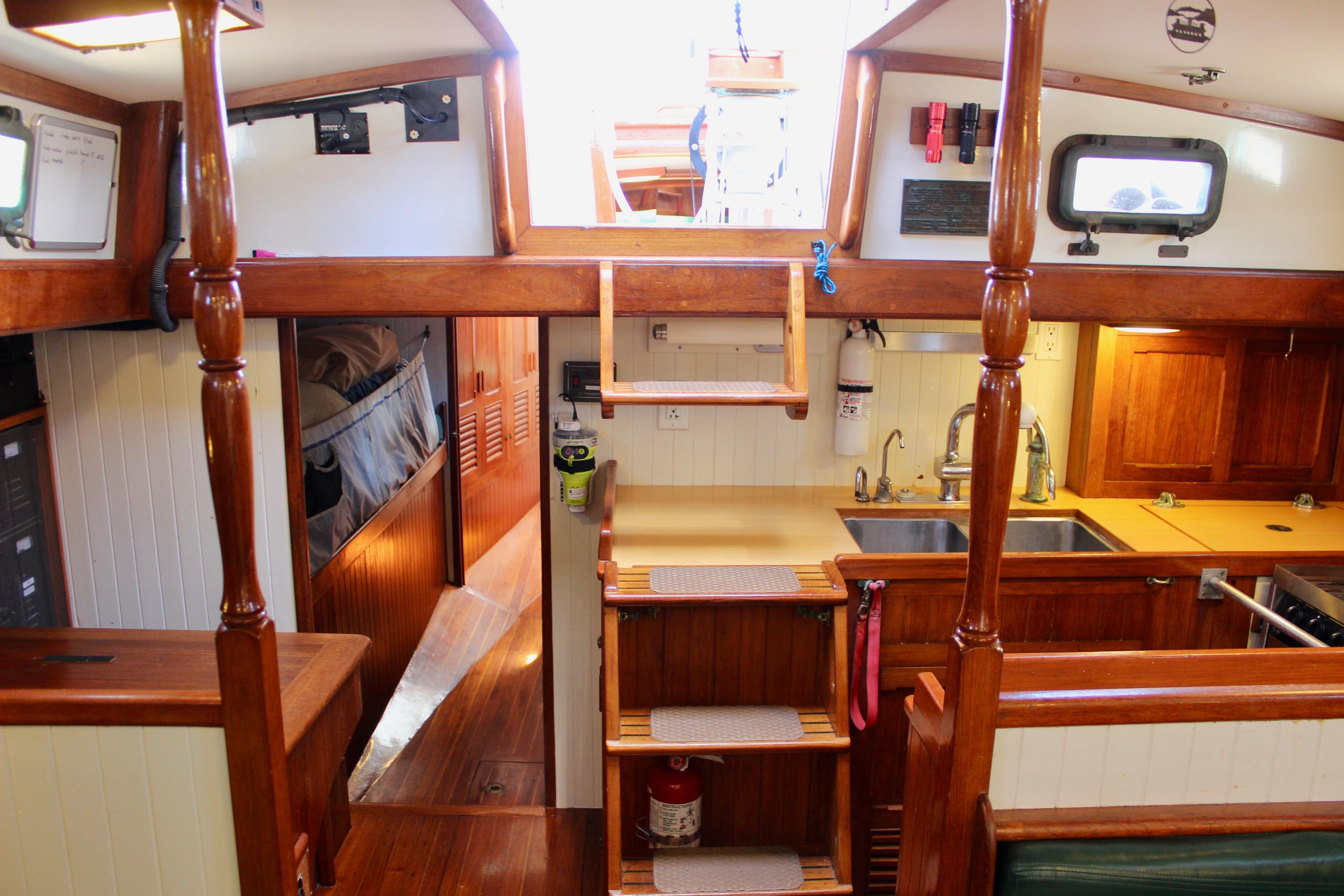 Interior of 1981 Kelly Peterson 46 sailboat with wooden finishes and compact kitchen.