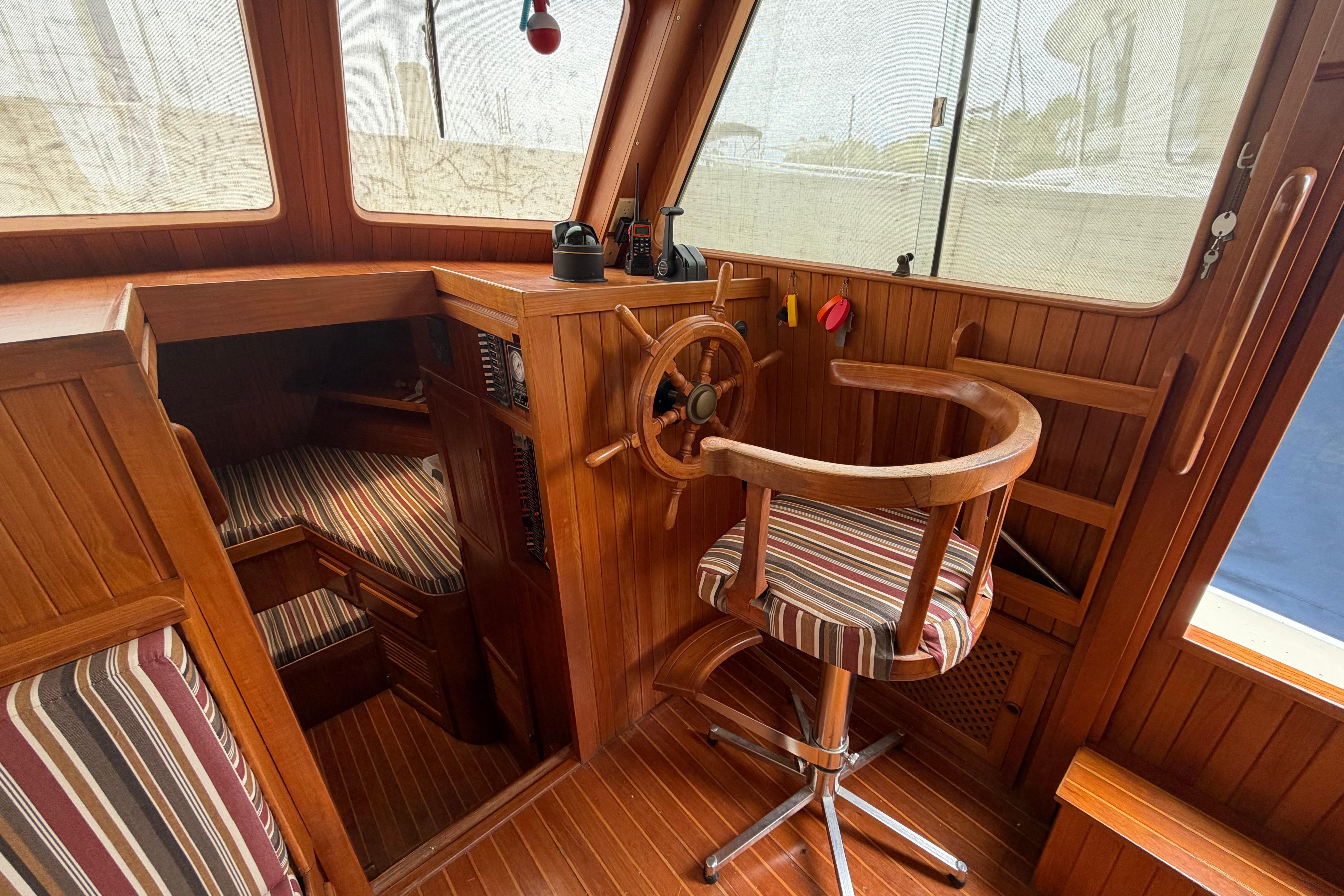 1988 Monk 36 boat interior with wooden helm, striped seating, and nautical decor.
