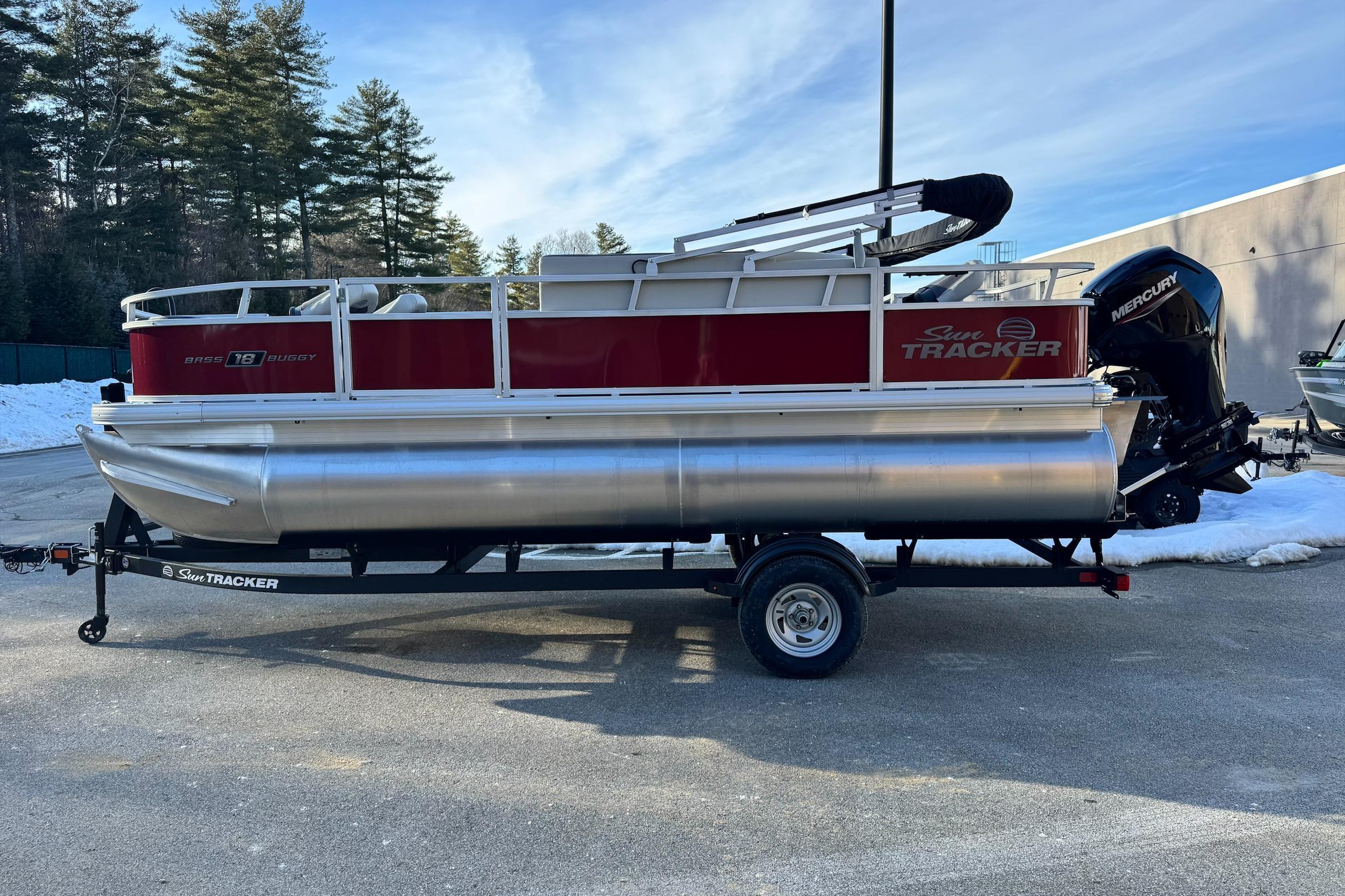 2026 Sun Tracker Bass Buggy 18 DLX pontoon boat on trailer, parked outdoors.