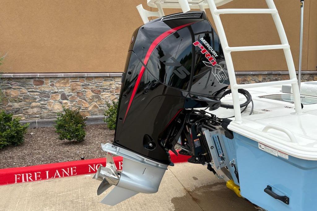 2026 Mako 18 Pro Skiff with Mercury Pro XS outboard motor, parked near stone wall.