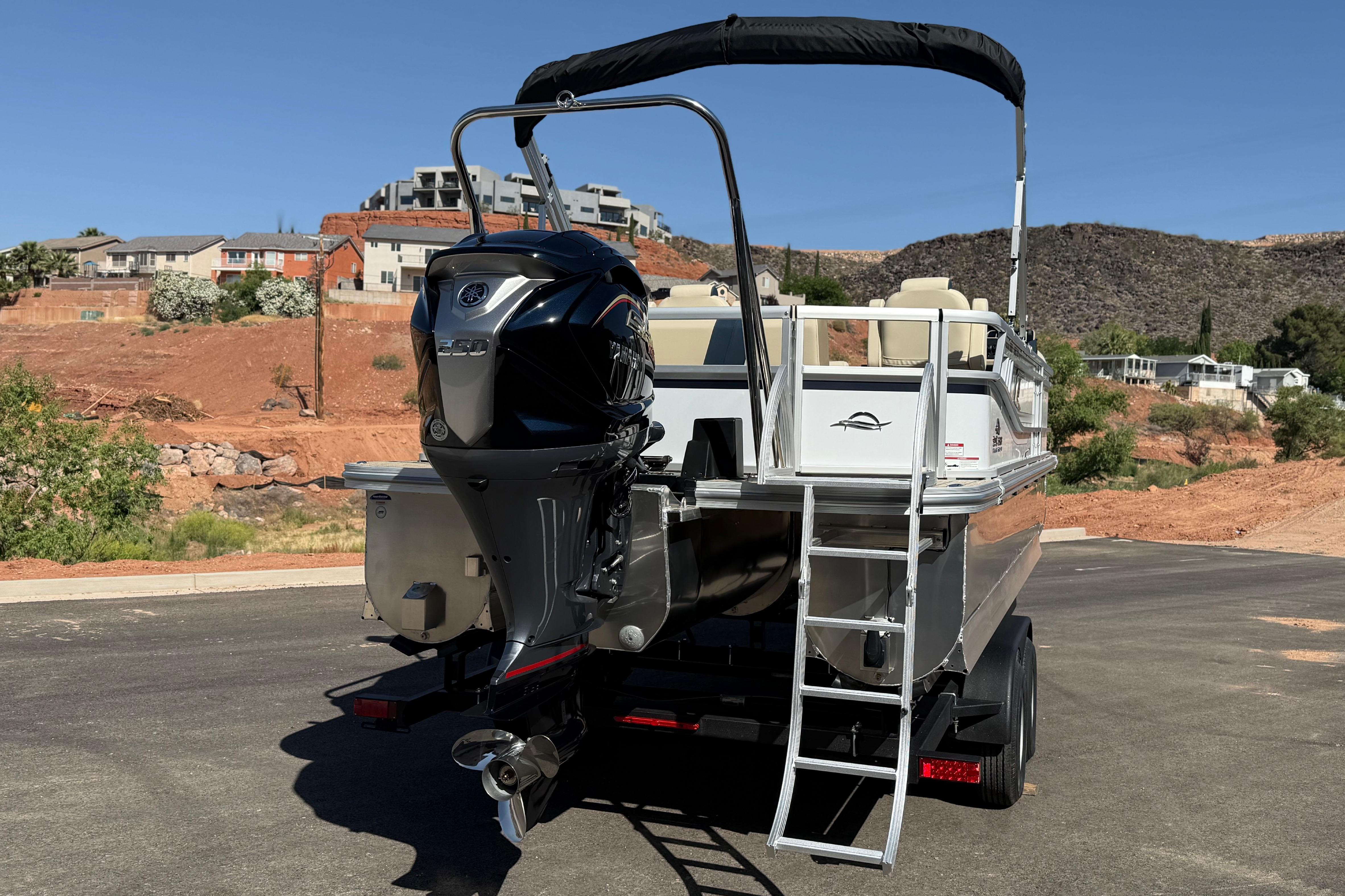 2026 SunCatcher Select 322SL pontoon boat with outboard motor and ladder, parked outdoors.