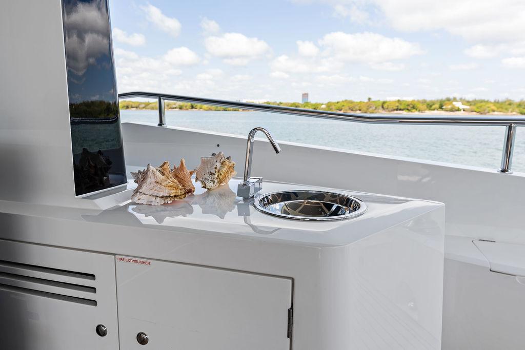 Luxury Sunseeker 86 Yacht 2019 with outdoor sink and seashells, overlooking serene waters.