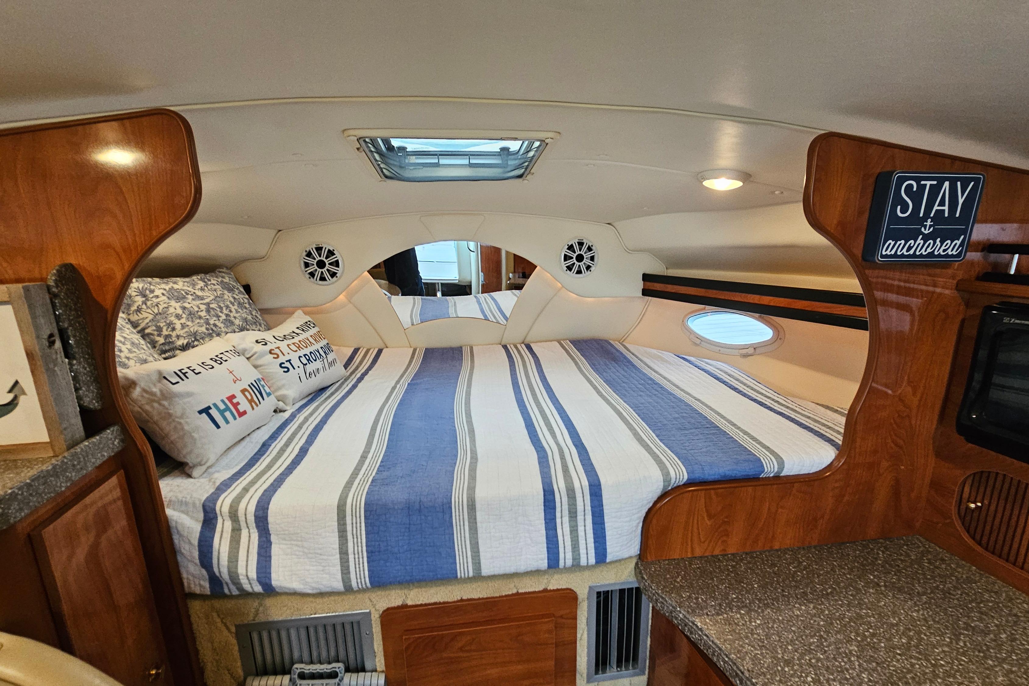 Cozy cabin interior of 2004 Rinker Fiesta Vee 312 with striped bedding and nautical decor.