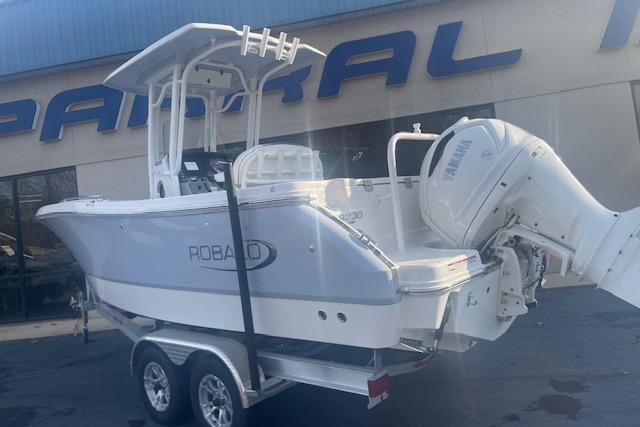 2024 Robalo R230 Center Console boat on trailer, displayed outside dealership.