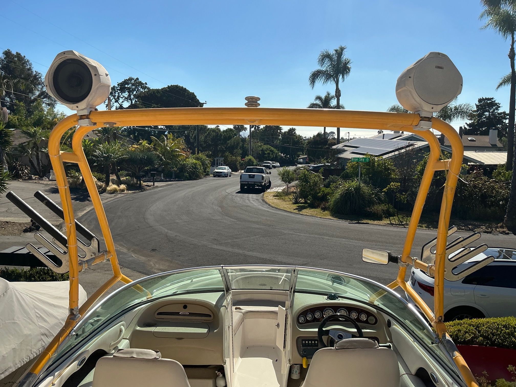 A 2003 Chaparral 210 SS boat with a yellow roll bar and speakers, parked in a residential area.
