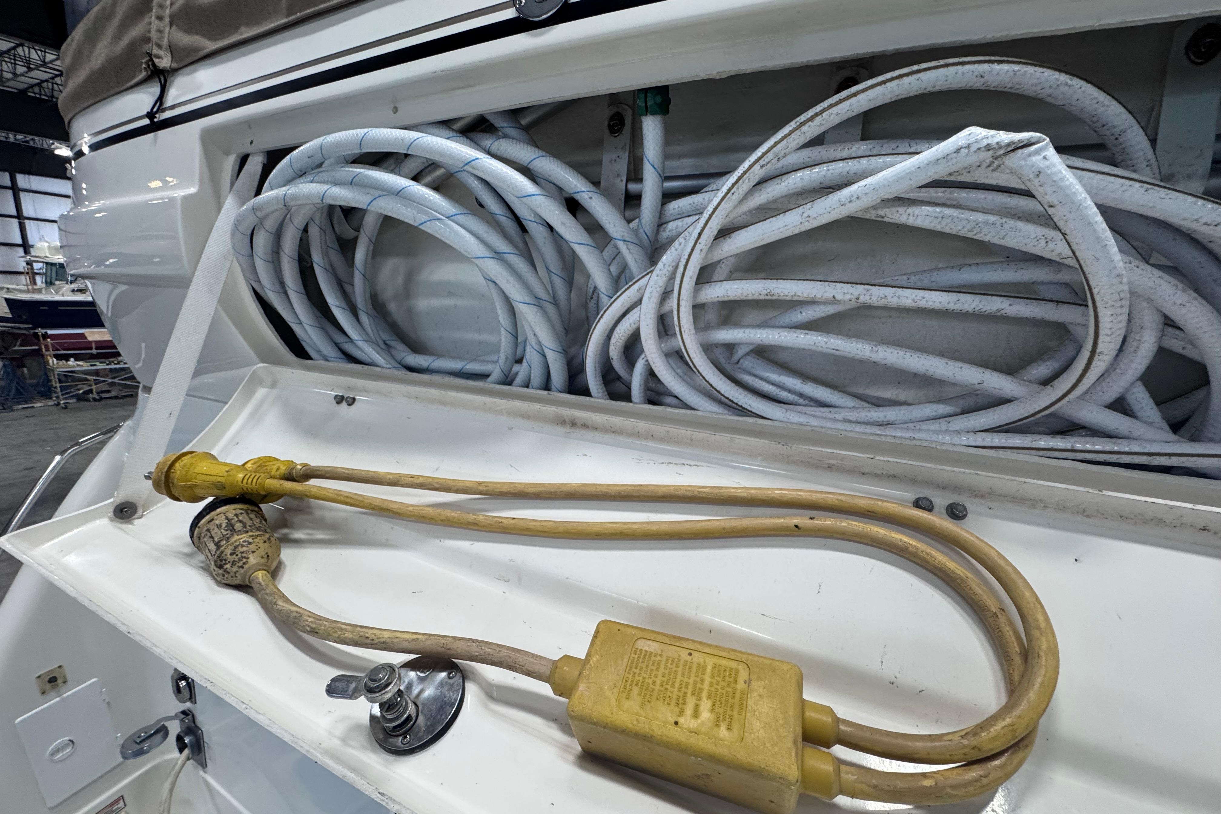 Storage compartment of a 2004 Sea Ray 390 Motor Yacht with coiled hoses and power cables.