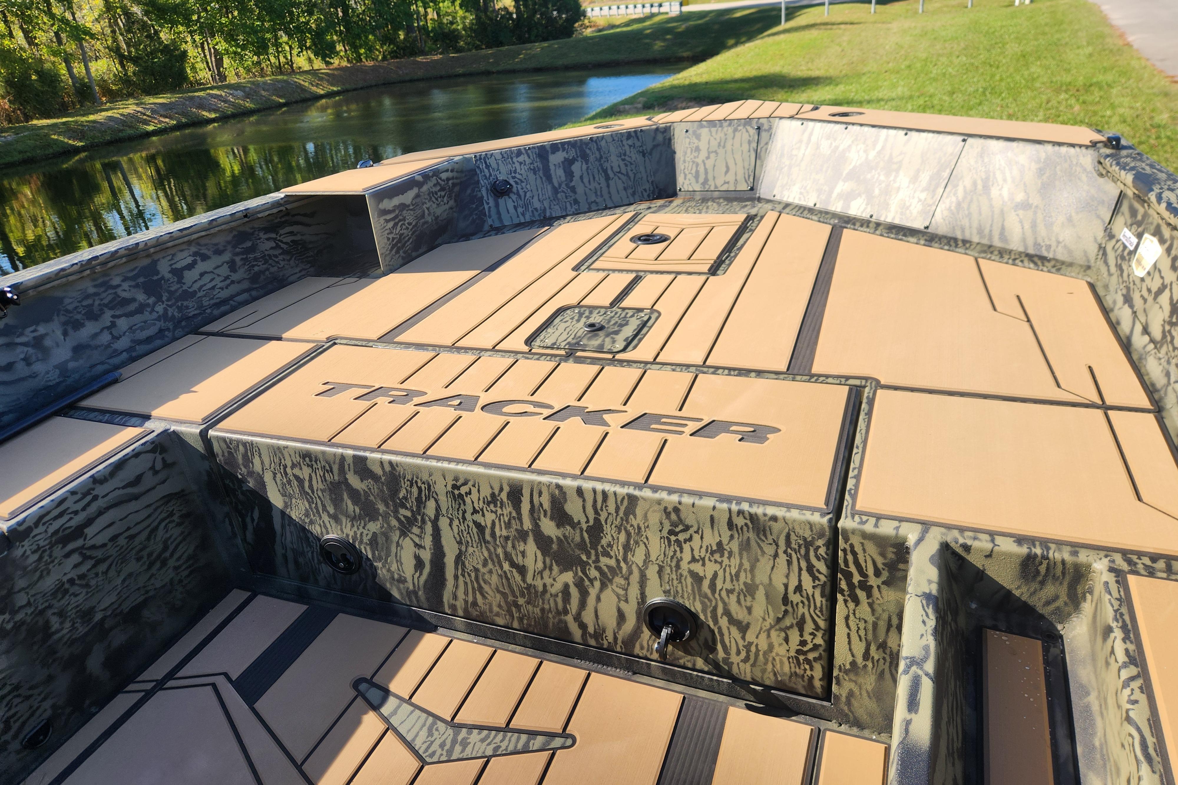 2026 Tracker Grizzly 1756 T Marsh boat with camo design near a serene waterway.