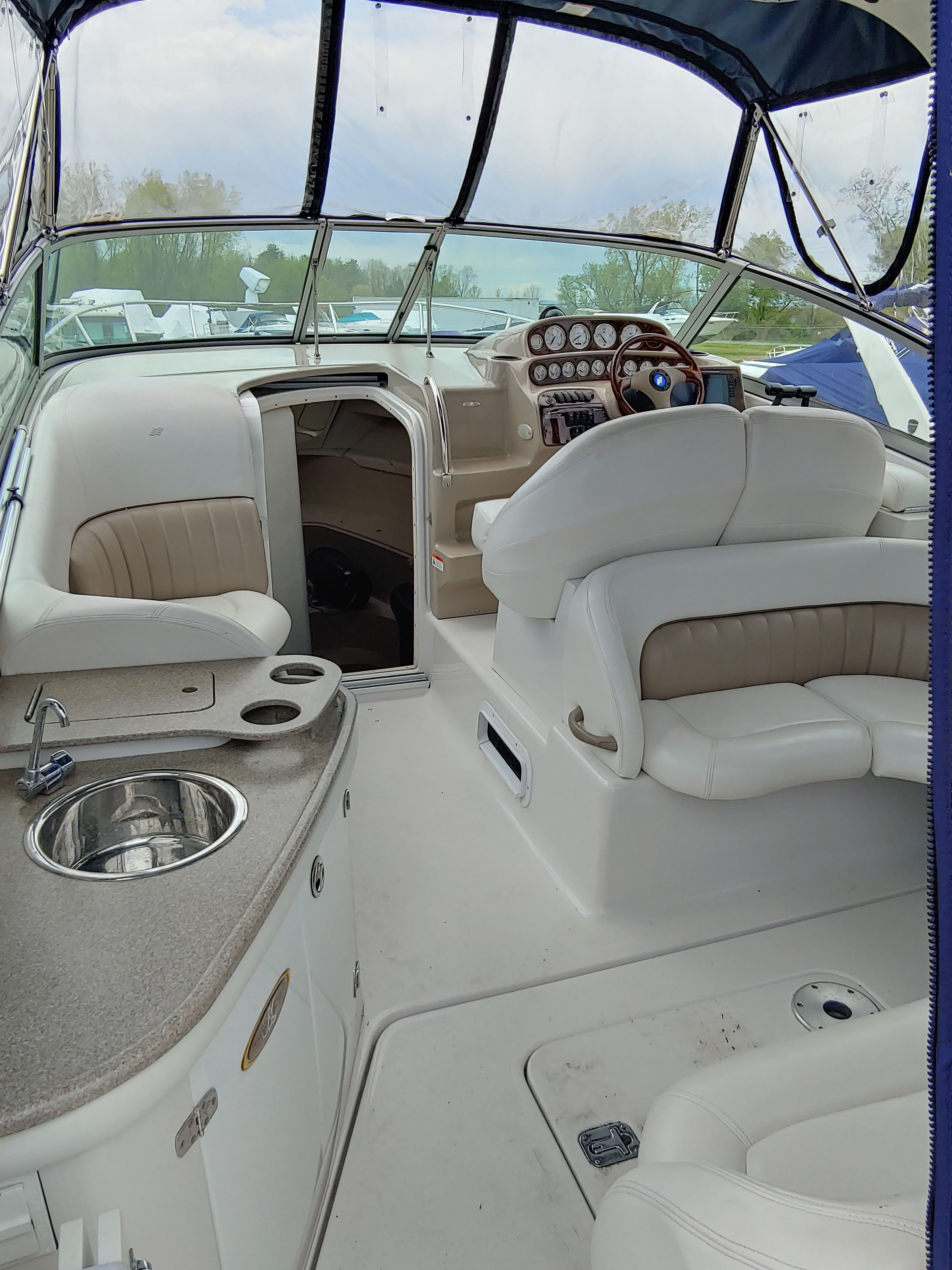 The boat features white seating, a sink, and a steering wheel with wood accents.