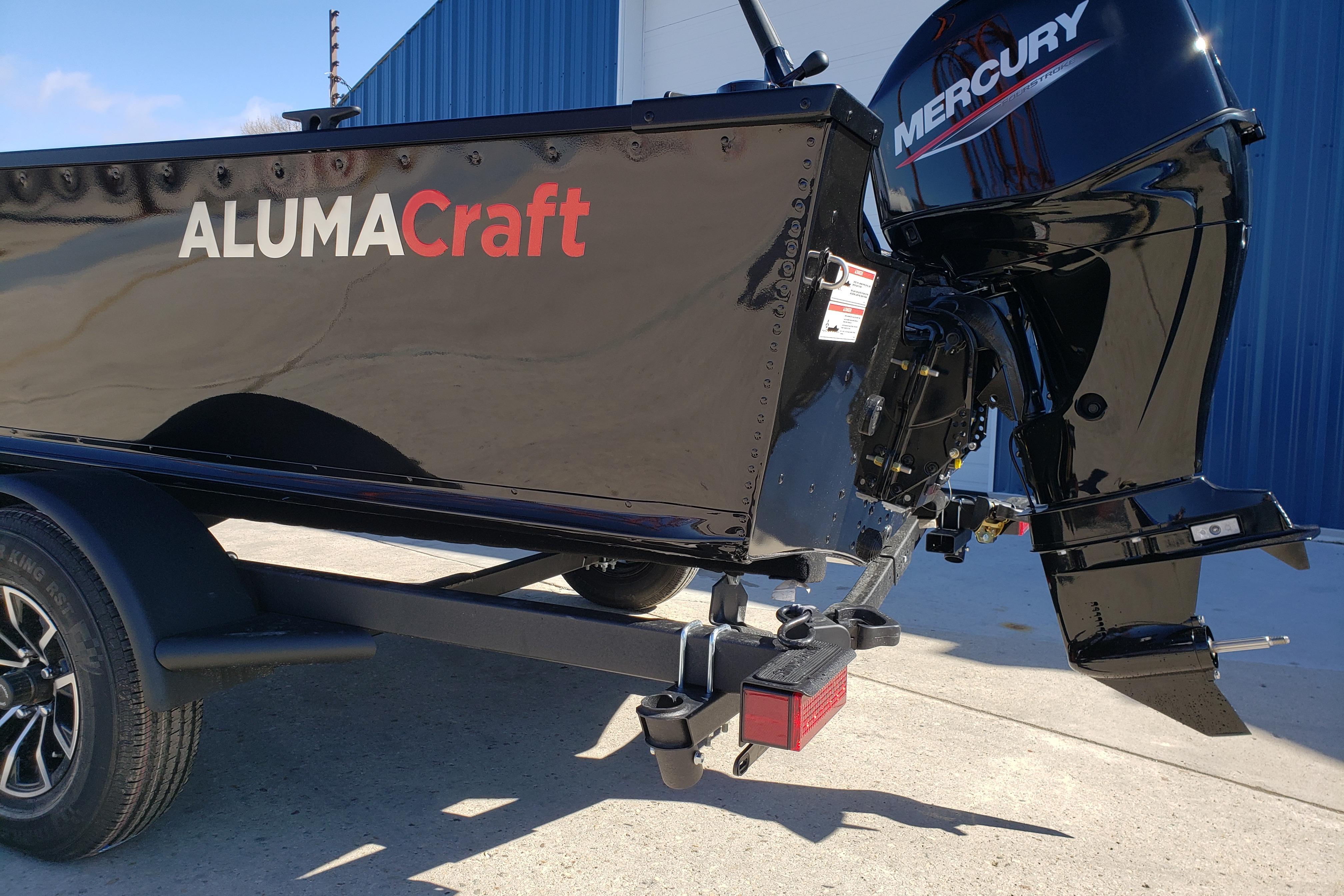 2026 Alumacraft Classic 165 Tiller boat with Mercury engine, parked outdoors.