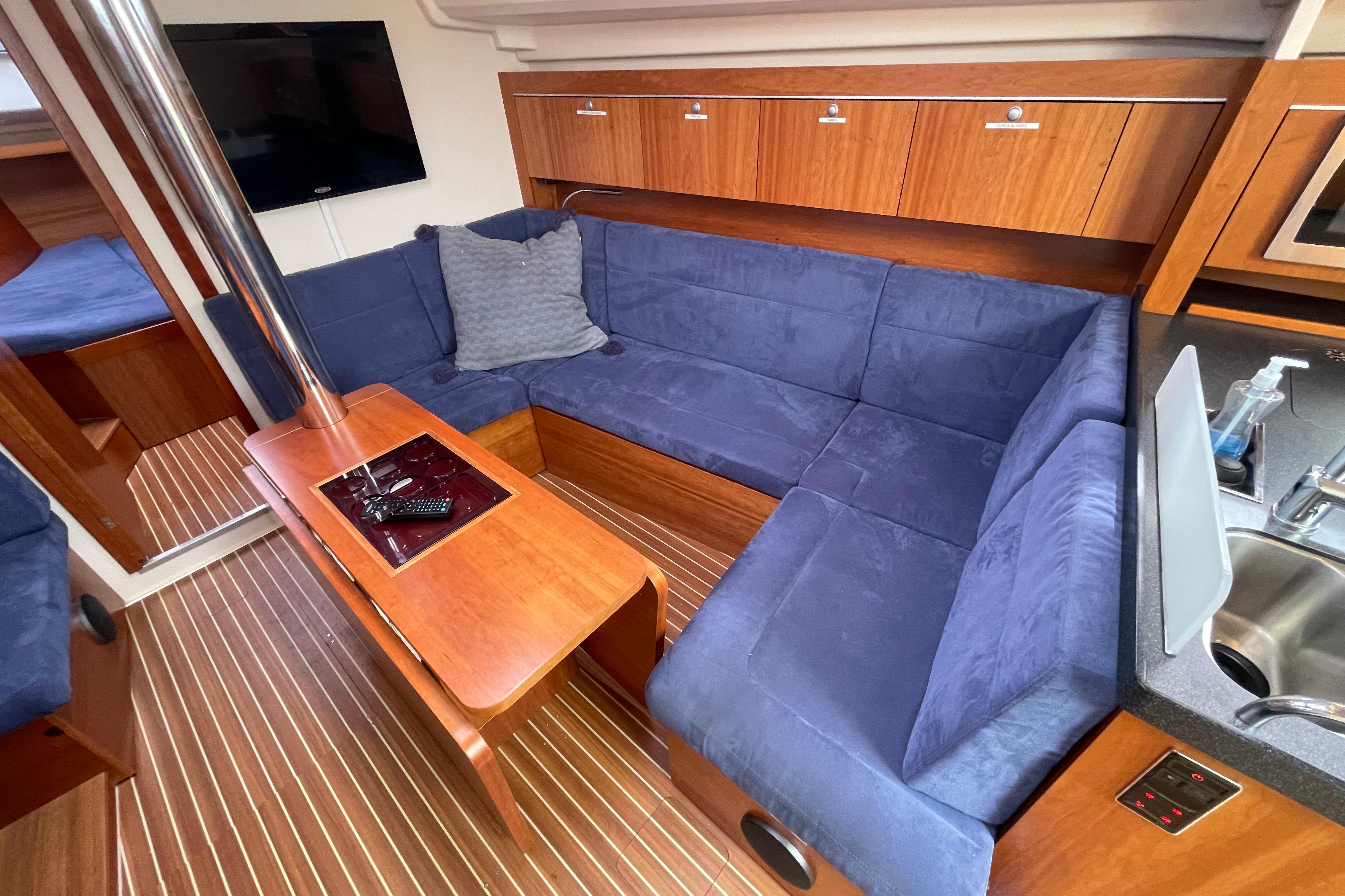 Interior of 2014 Hanse 415 yacht with blue seating, wooden table, and modern amenities.