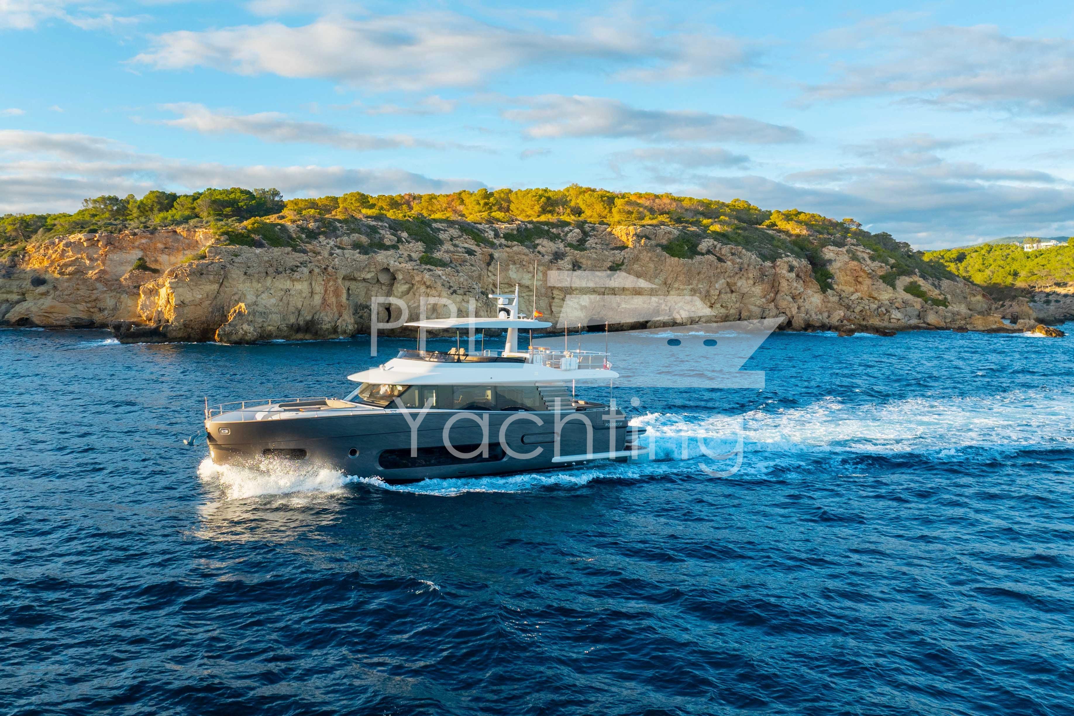 Azimut Magellano 66 yacht cruising near rocky coastline under a blue sky, 2021 model.
