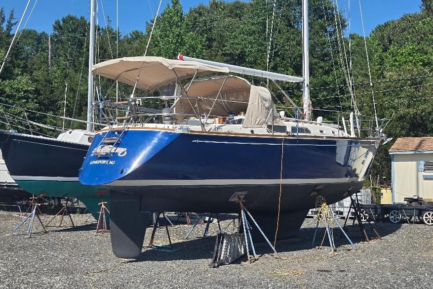 1988 Sabre 38 sailboat on stands, blue hull, outdoor storage, surrounded by trees.