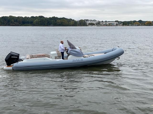 2024 SACS Strider 900 boat cruising on a calm lake with a person at the helm.