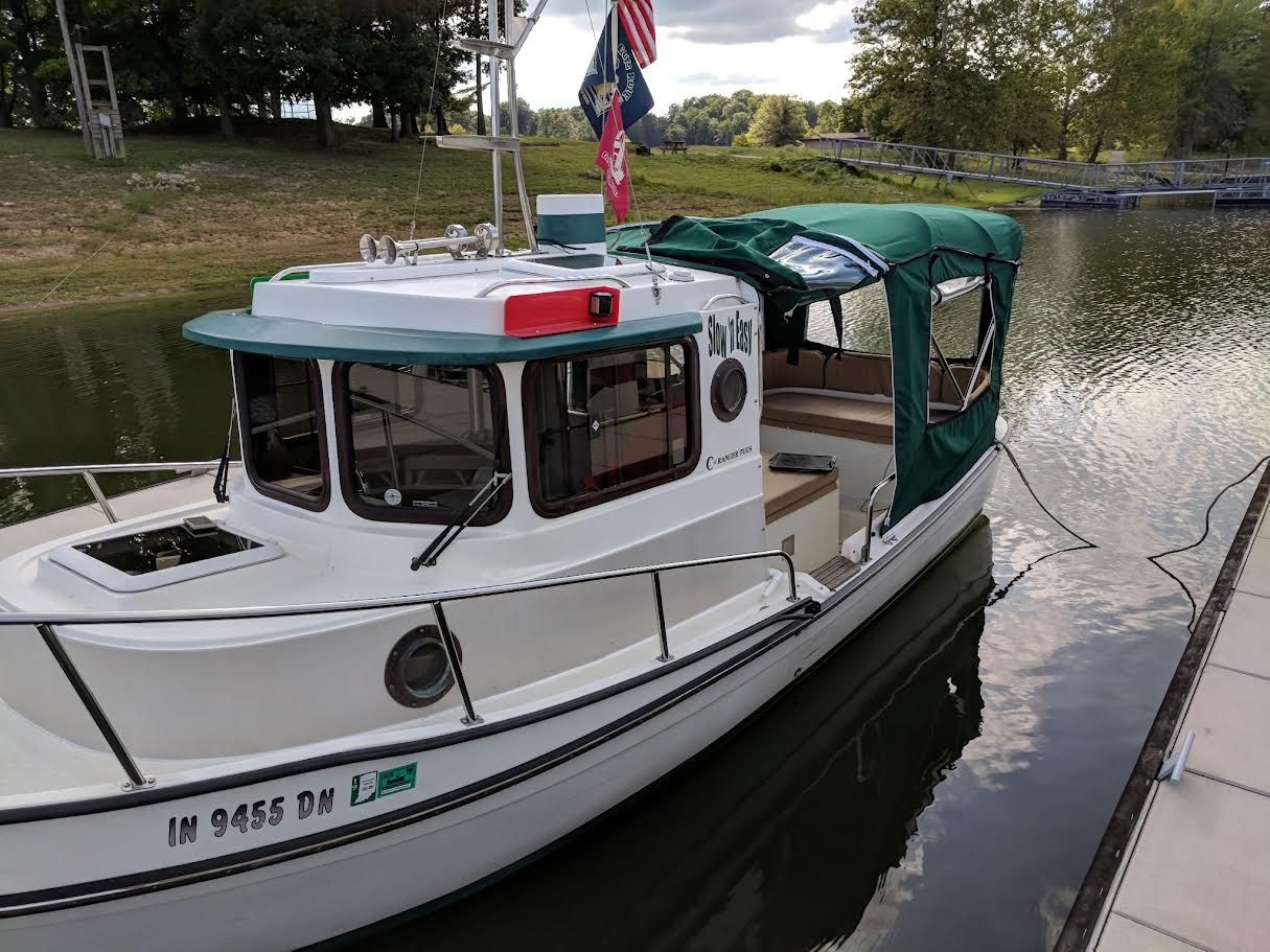 2007 Ranger Tugs R-21 EC at dock with green canopy and flags.