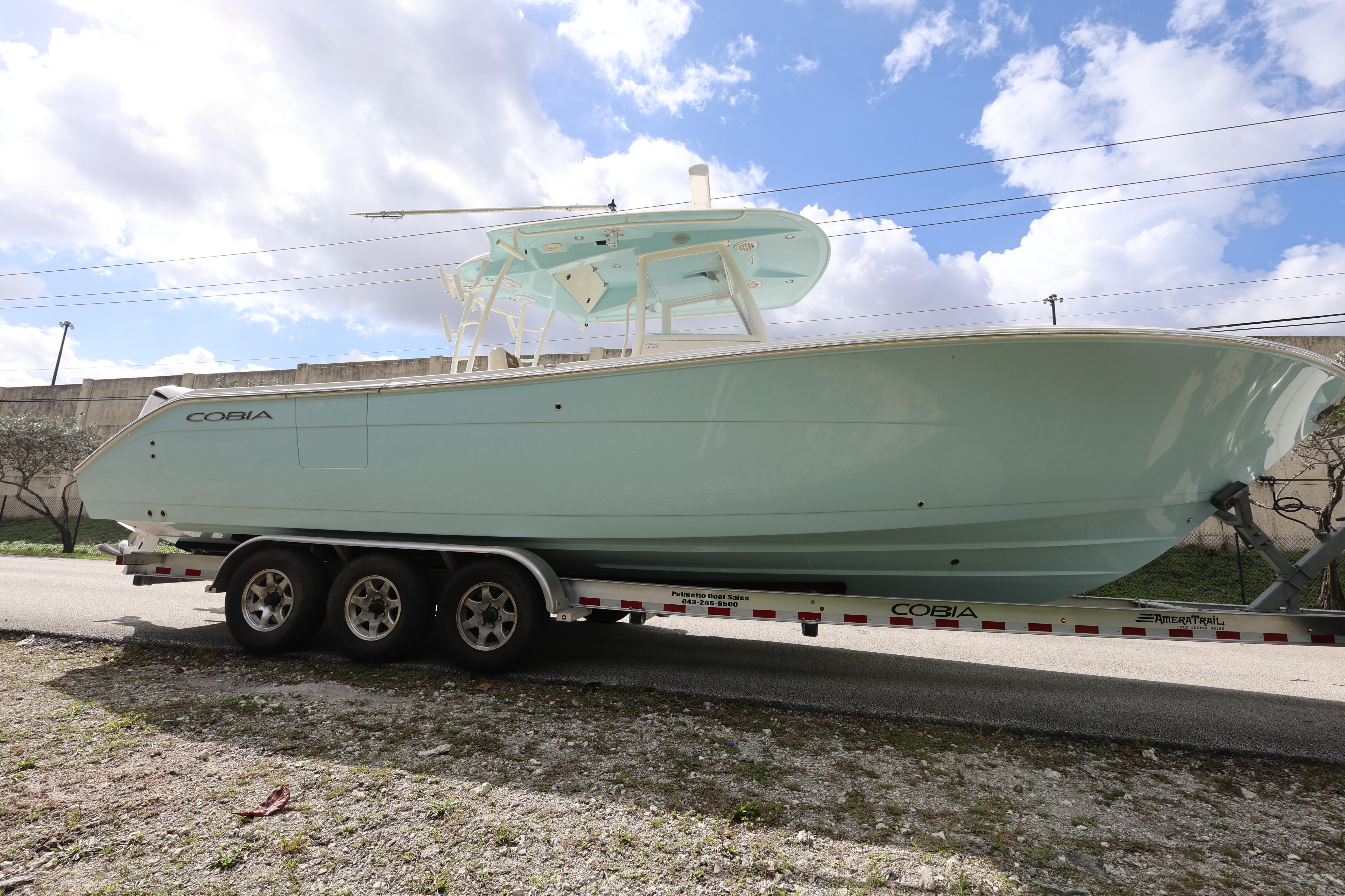 2019 Cobia 320 Center Console boat on trailer under cloudy sky.