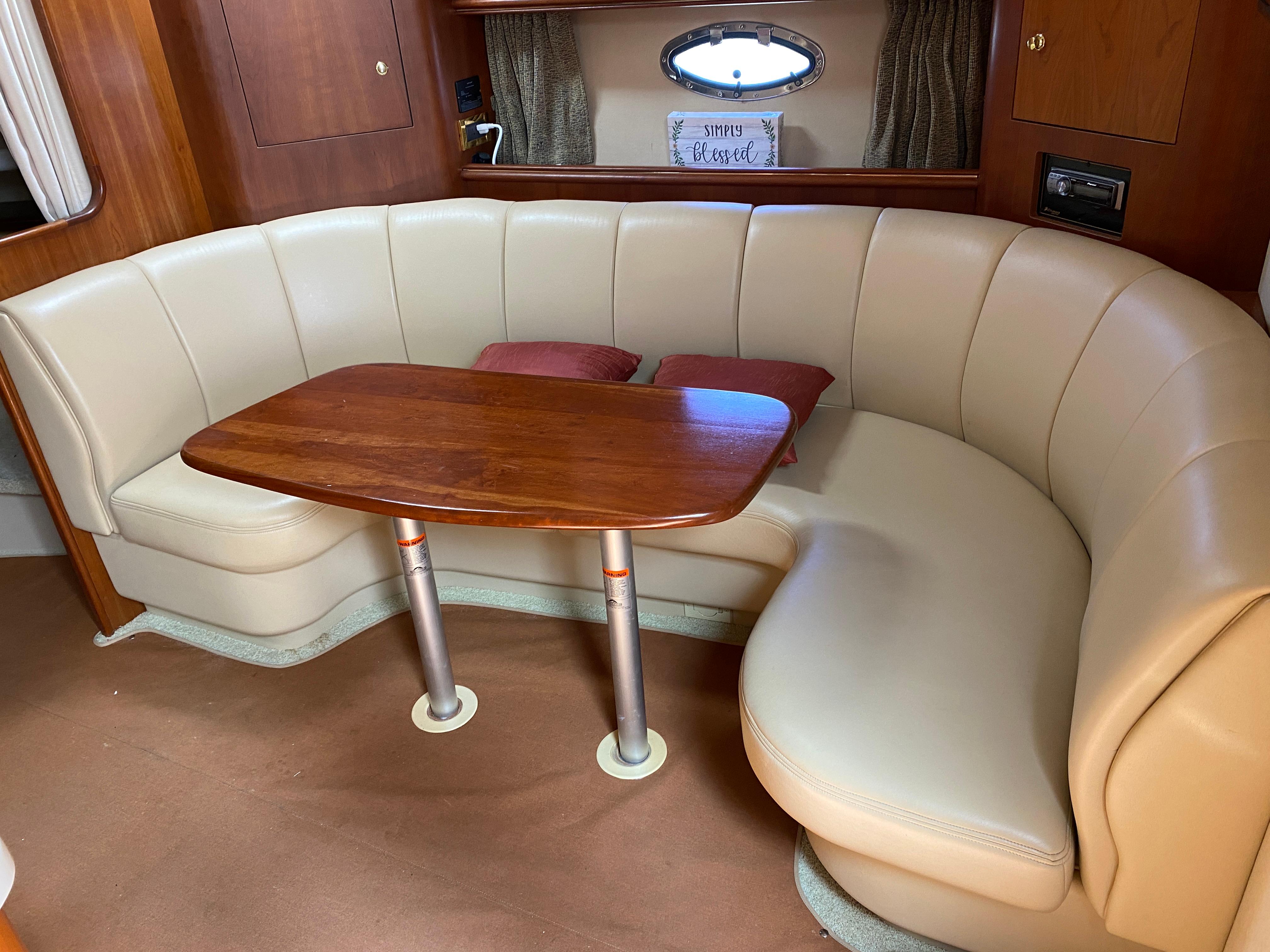 Luxurious 2000 Cruisers 3672 yacht interior with curved leather seating and wooden table.