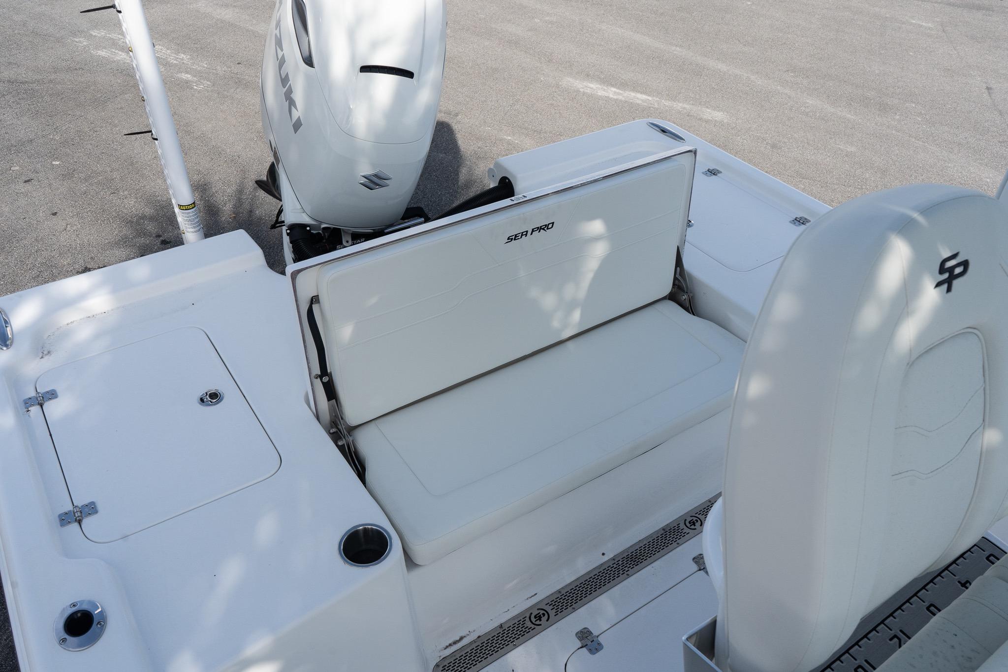 2026 Sea Pro 250 Bay boat interior with Suzuki engine, featuring white seating and storage compartments.